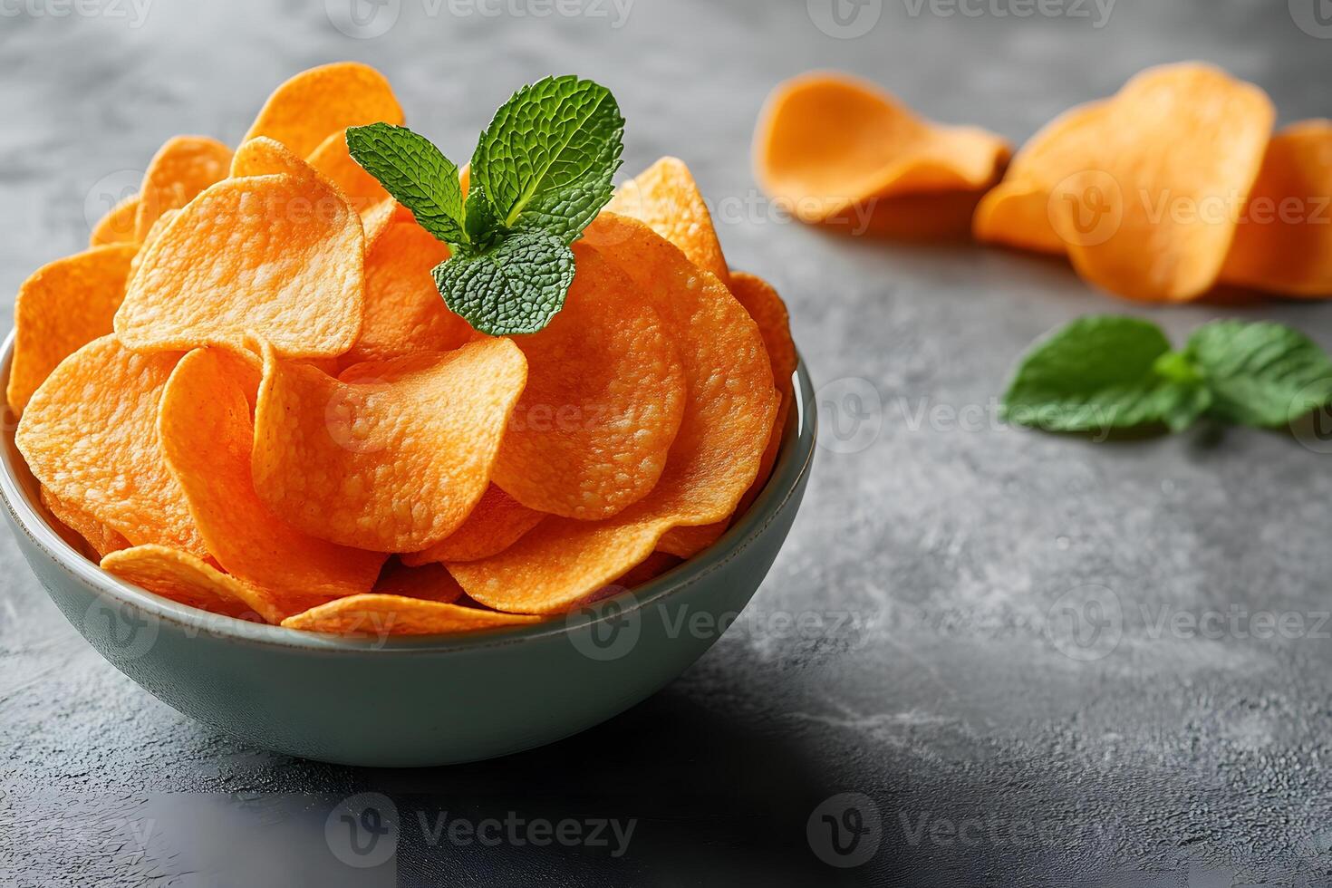 Bowl of Crunchy Potato Chips with Mint Garnish on Rustic Stone Surface photo