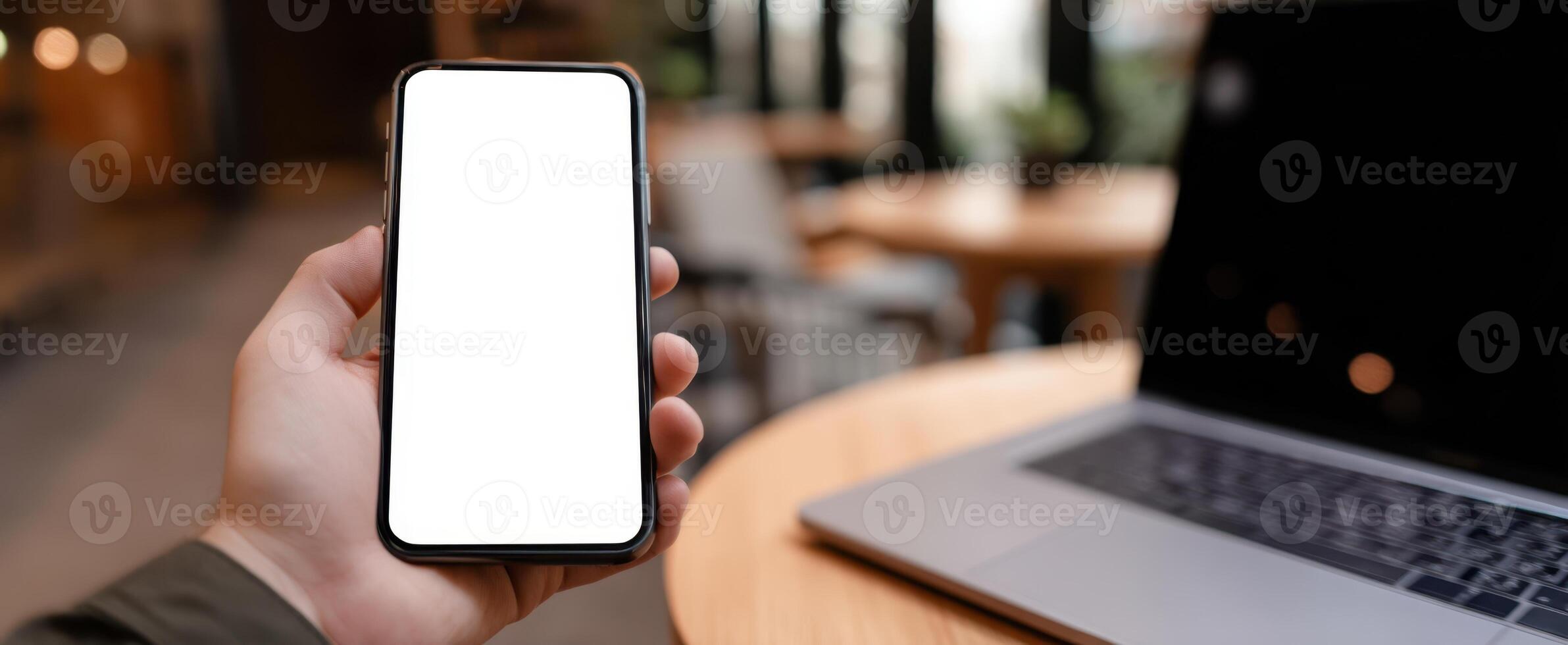 The smartphone in hand showcasing a blank screen in a modern workspace. photo