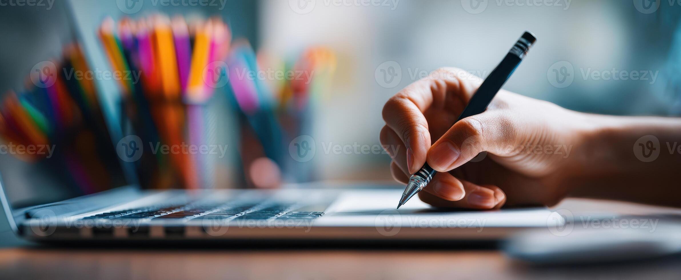 The hand writing notes on a laptop in a creative workspace. photo