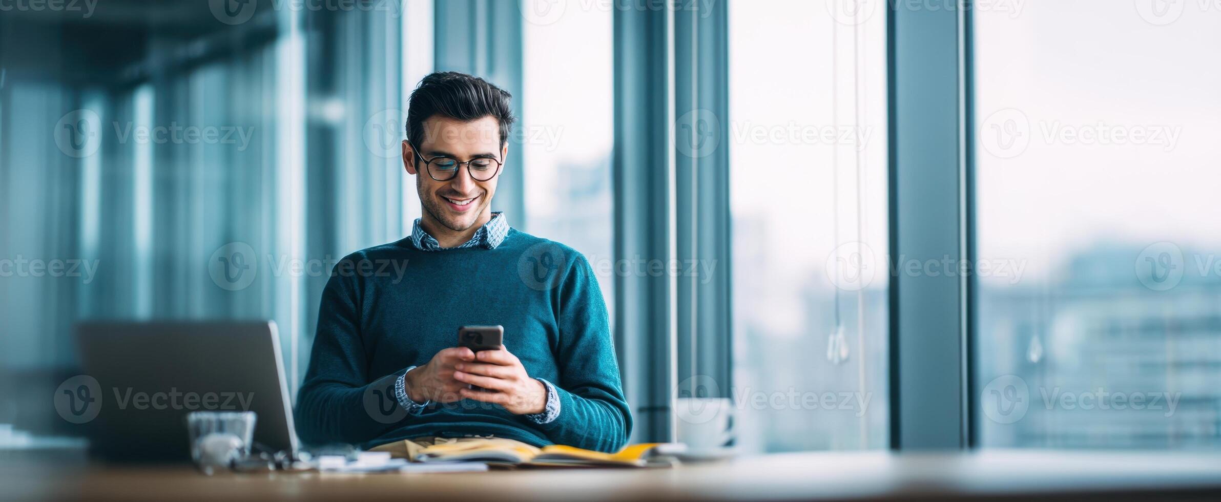 The young man smiles while using his smartphone in a modern office. photo