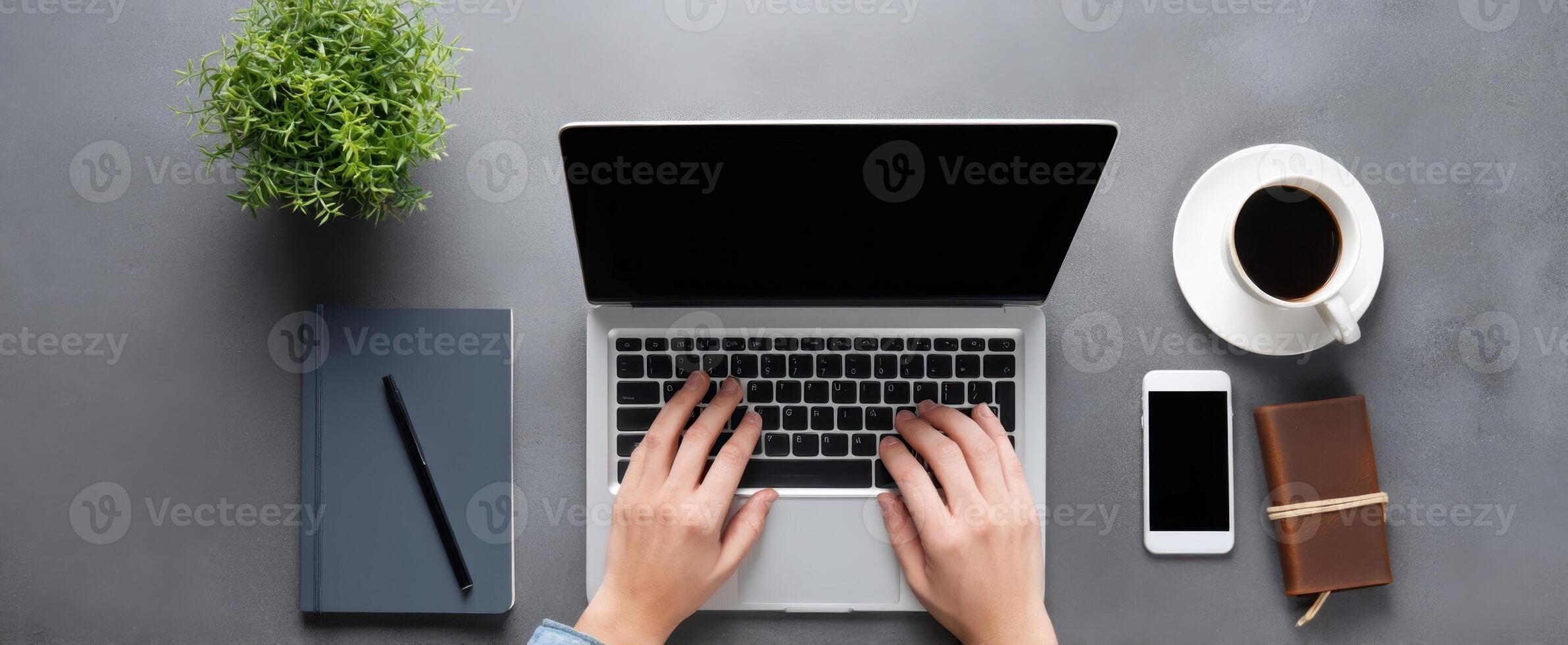 The laptop on a desk surrounded by coffee and stationery items. photo