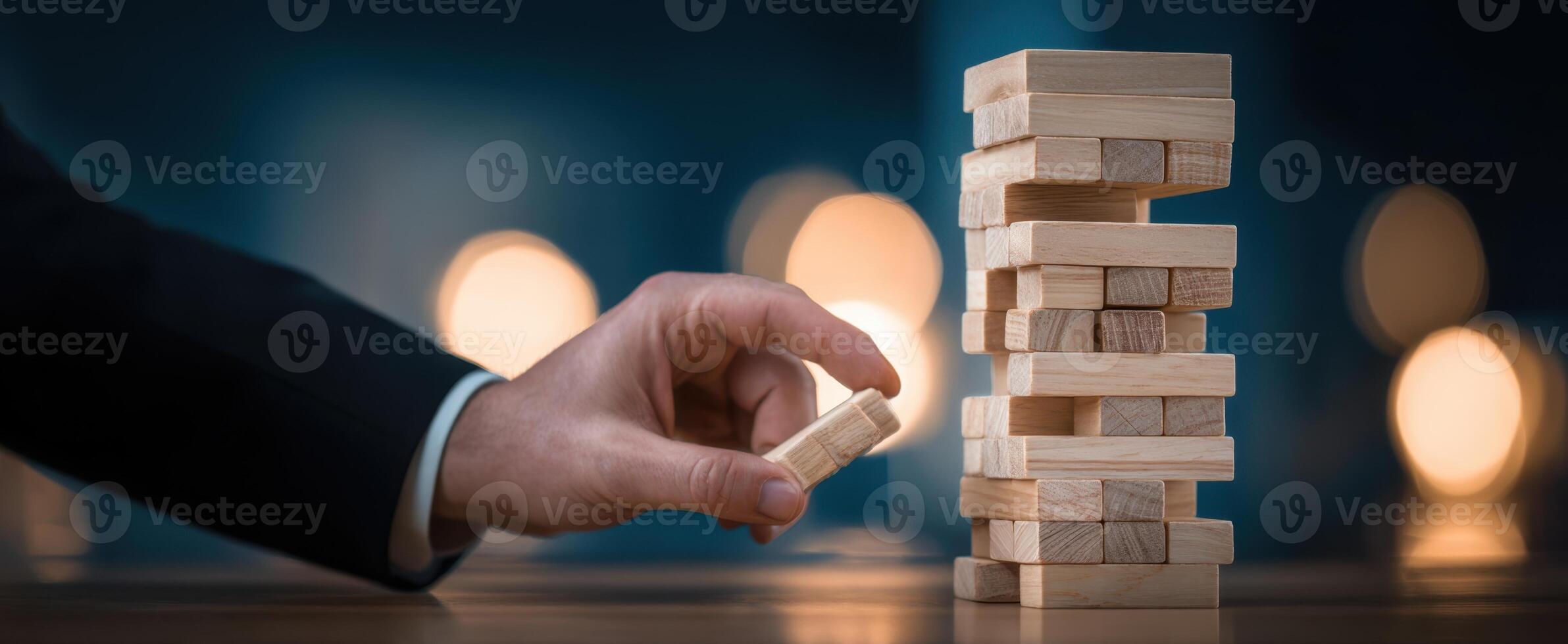 The hand carefully removes a block from a Jenga tower during gameplay. photo