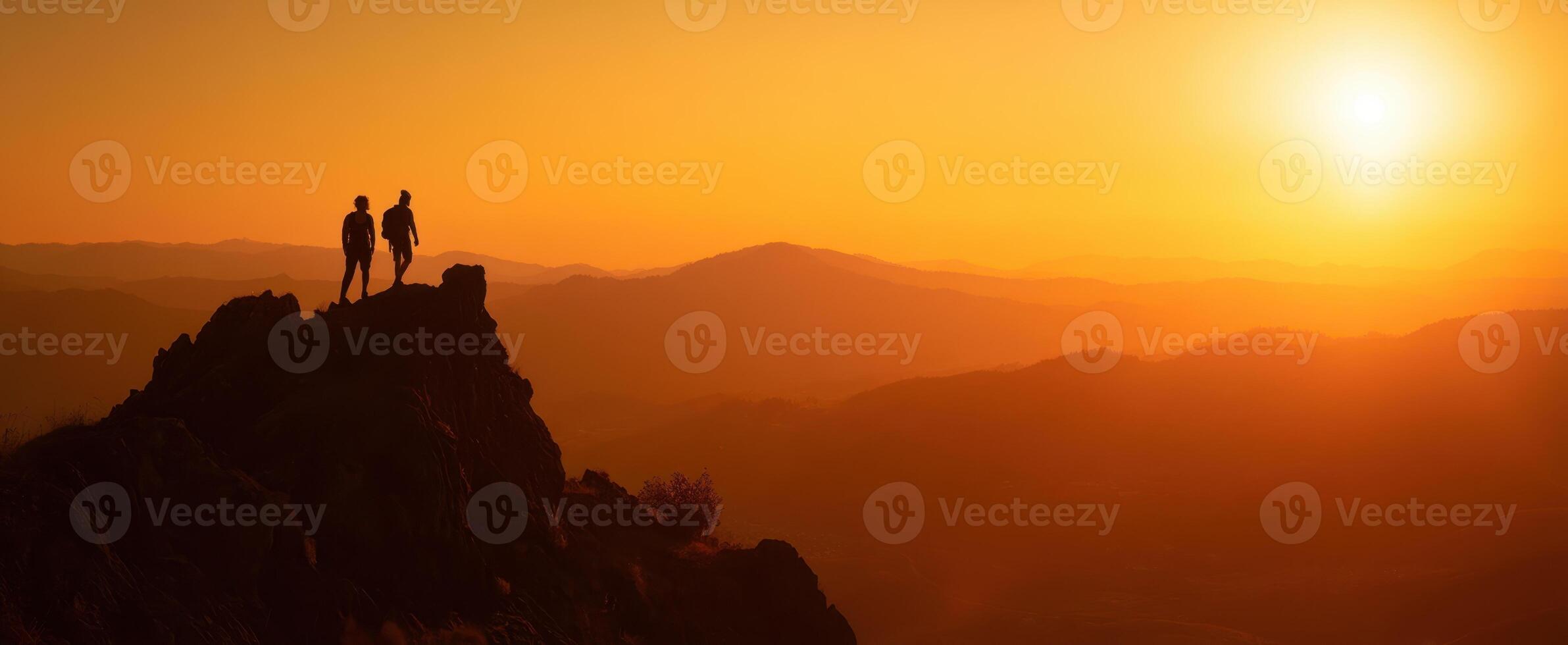 The hikers enjoying a breathtaking sunset view on the mountain peak. photo