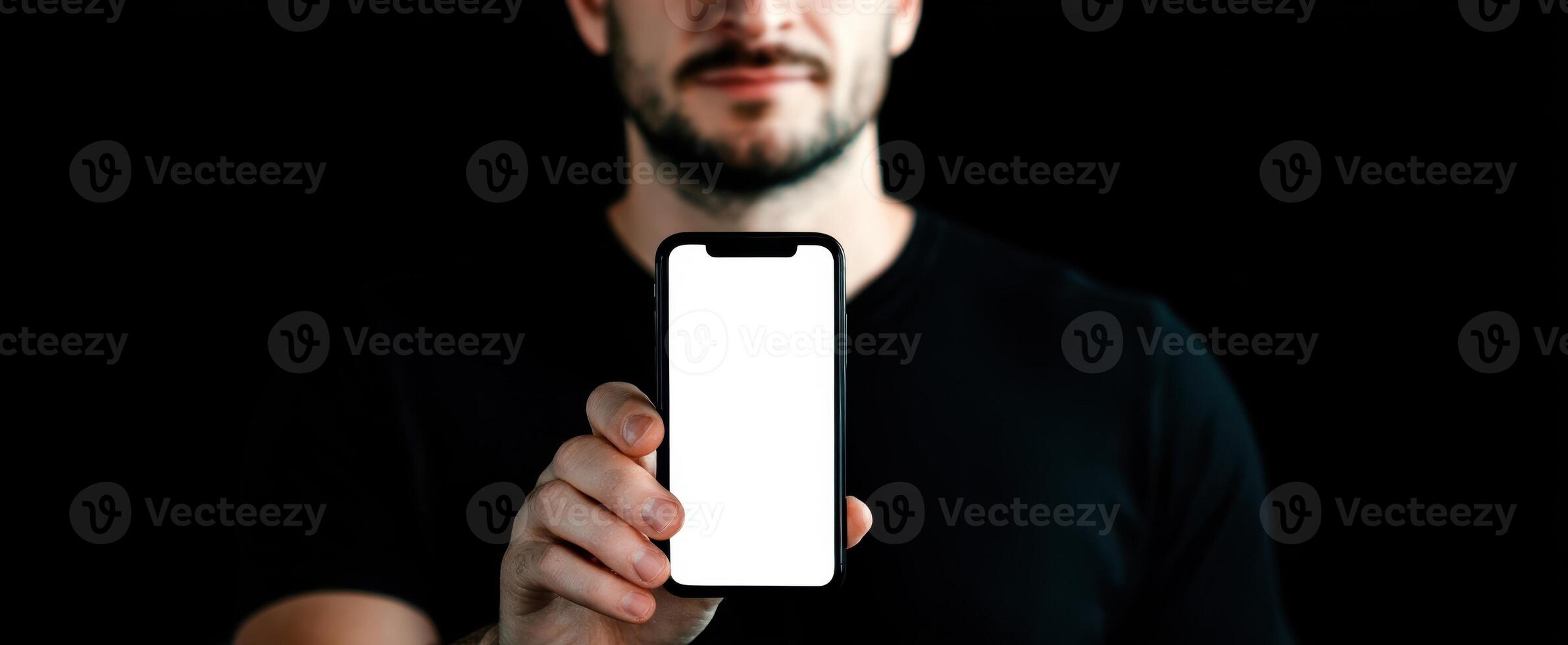 The man holding a smartphone with a blank screen in a dark setting. photo