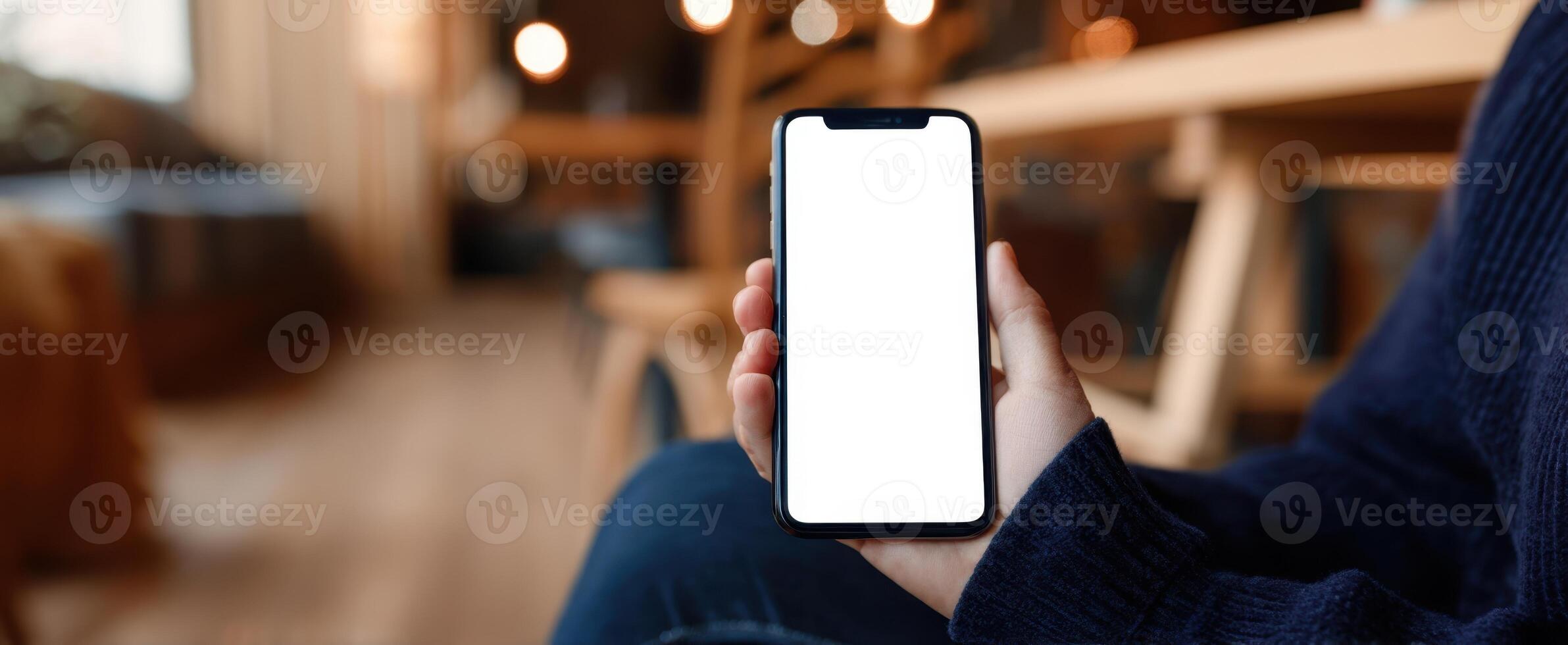 The smartphone held in a cozy cafe setting with a blank screen. photo