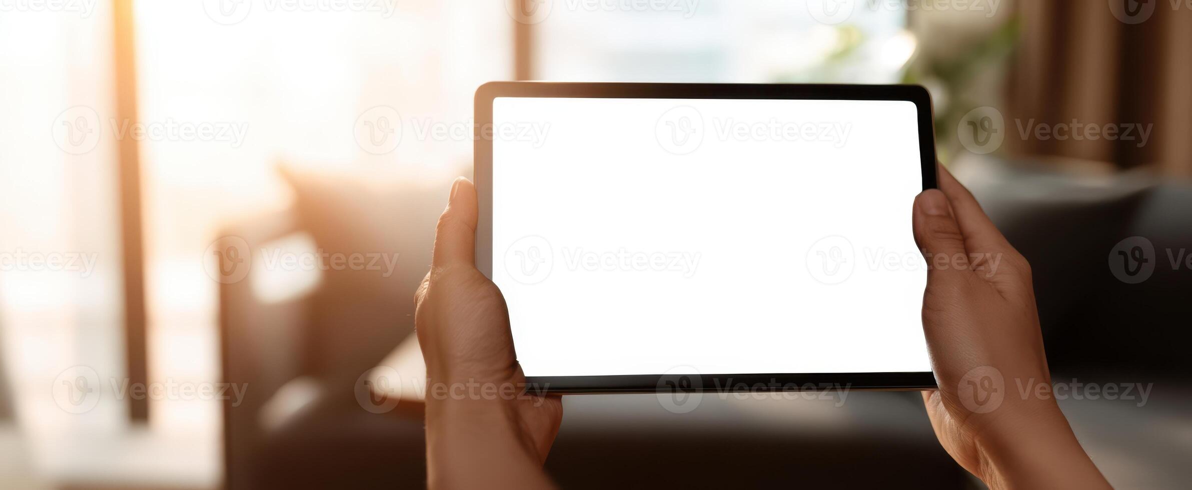 The modern tablet held by hands in a cozy home setting with natural light. photo