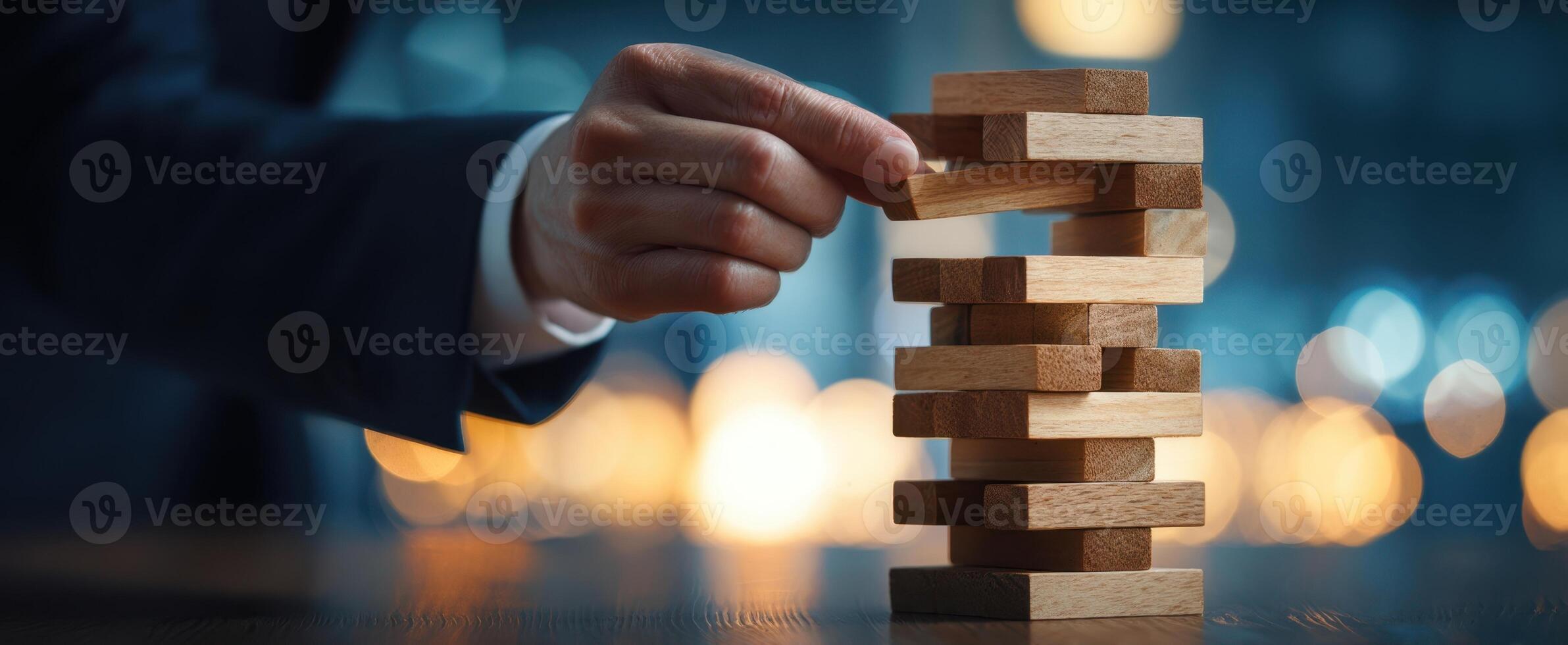 The hand carefully removes a block from a Jenga tower in a strategic challenge. photo