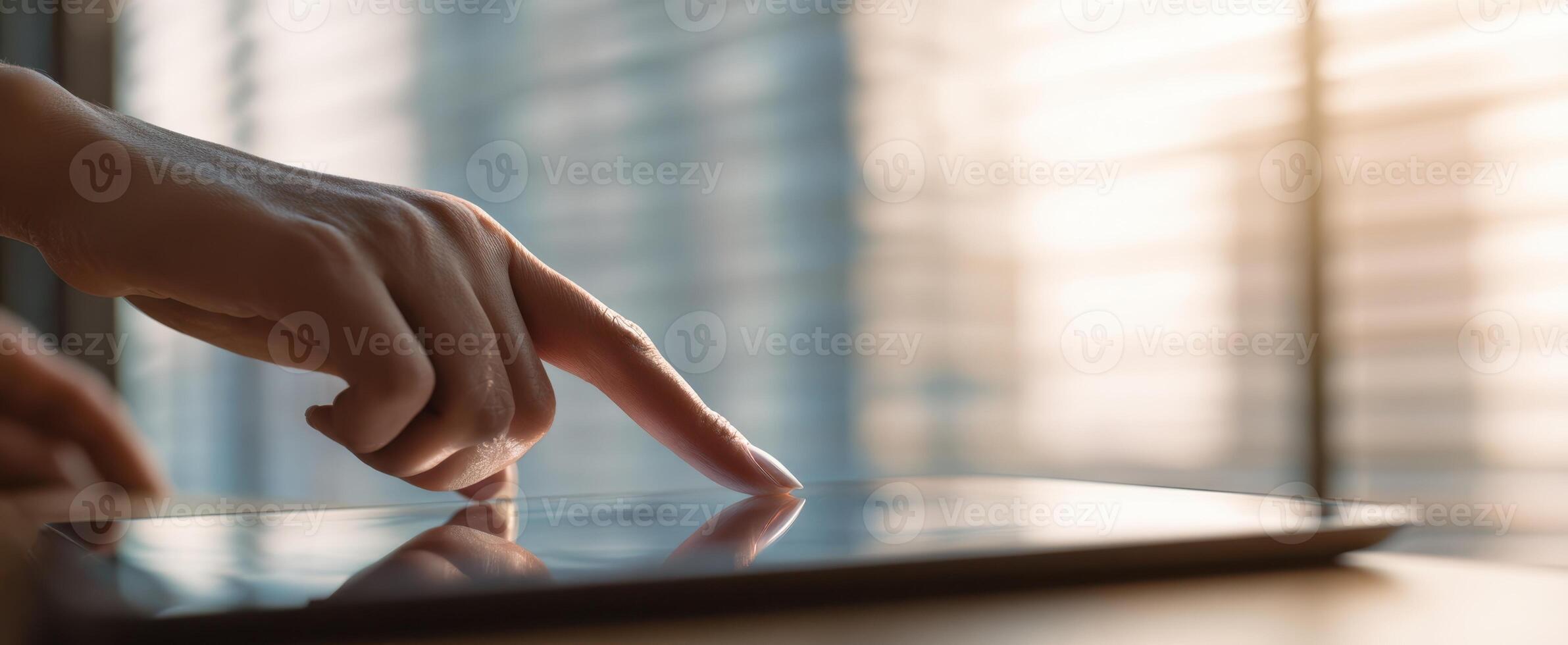 The hand interacting with a touchscreen tablet in a modern workspace setting. photo