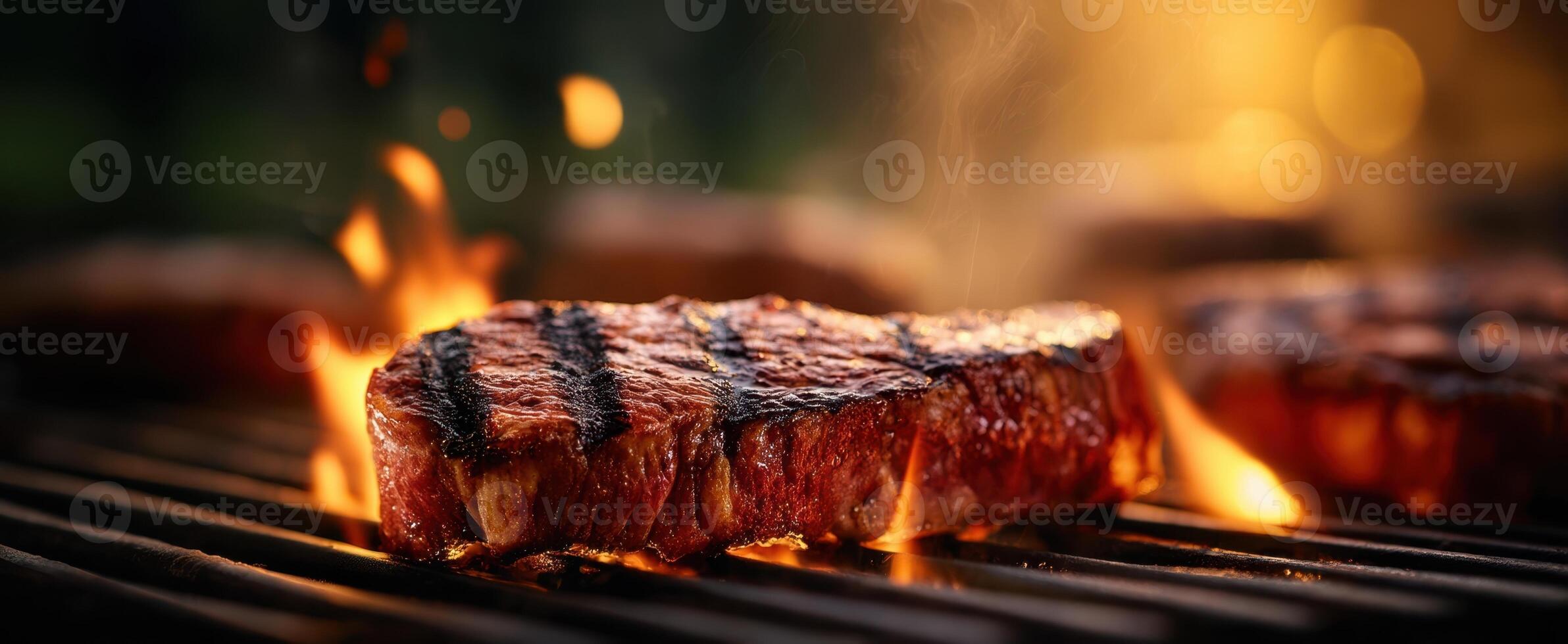 The sizzling steak on a grill with flames and smoke in a summer evening. photo