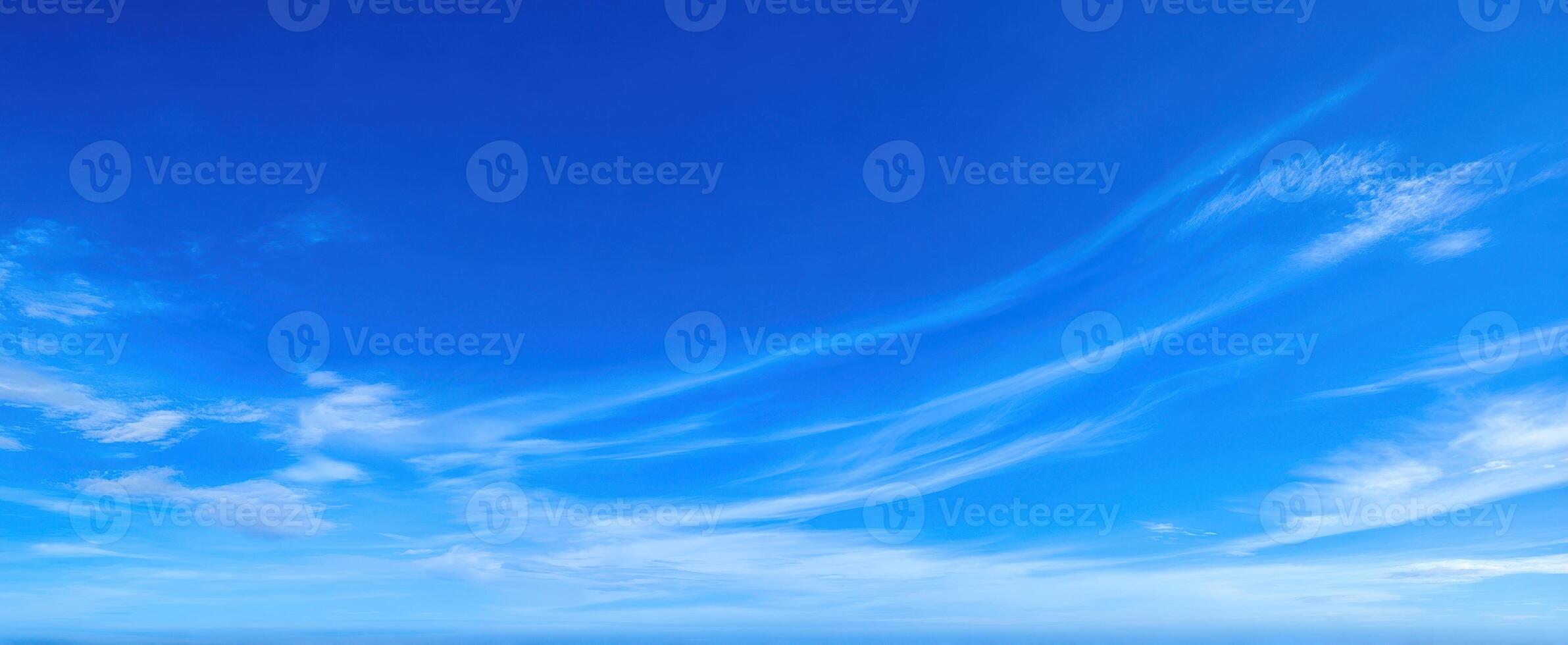 The serene blue sky with soft, wispy clouds hovering above the horizon. photo