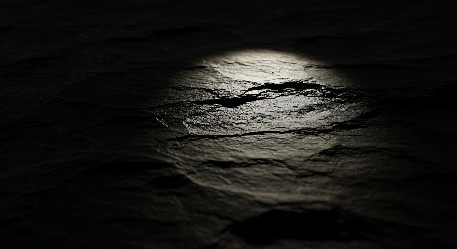 A dark rock surface with a light shining through it photo