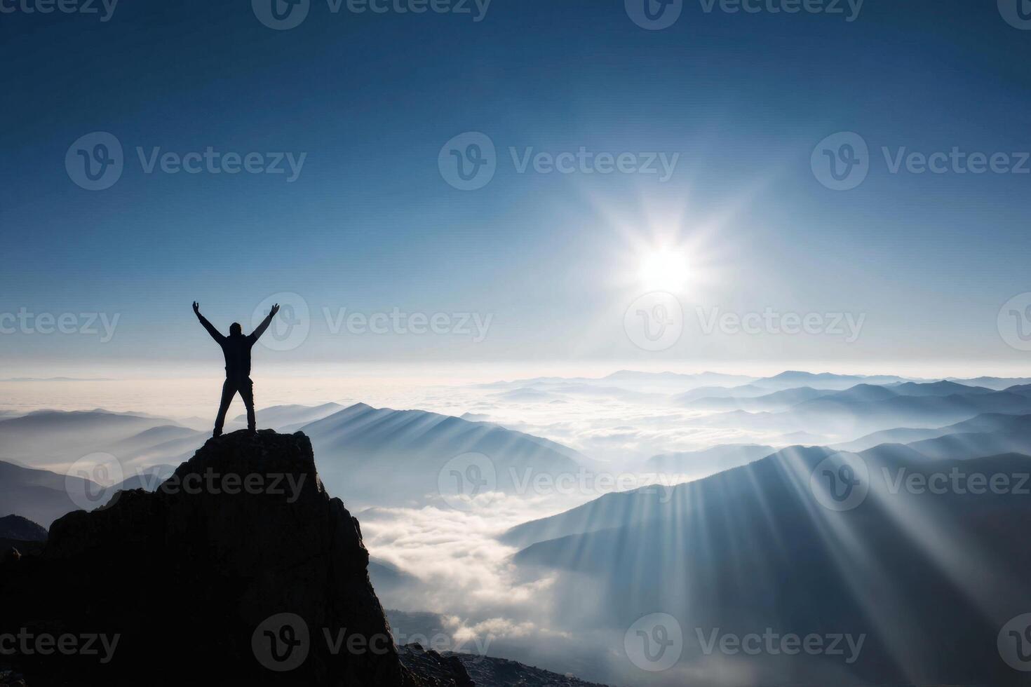Silhouette Man Standing on Mountain Top Achieving Success Over Clouds During Sunrise photo