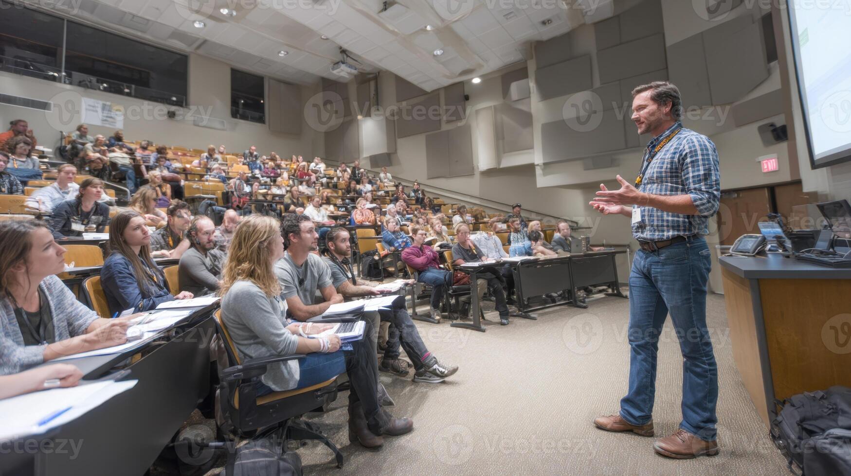 Man Delivering Presentation in an Auditorium Full of Students Taking Notes photo