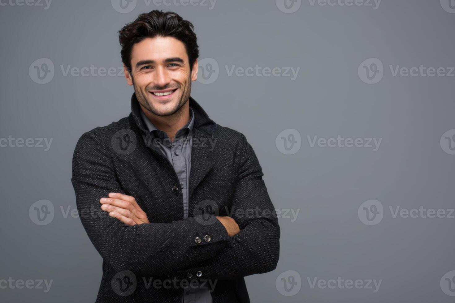 A happy and smiling man wearing a black coat with arms crossed photo