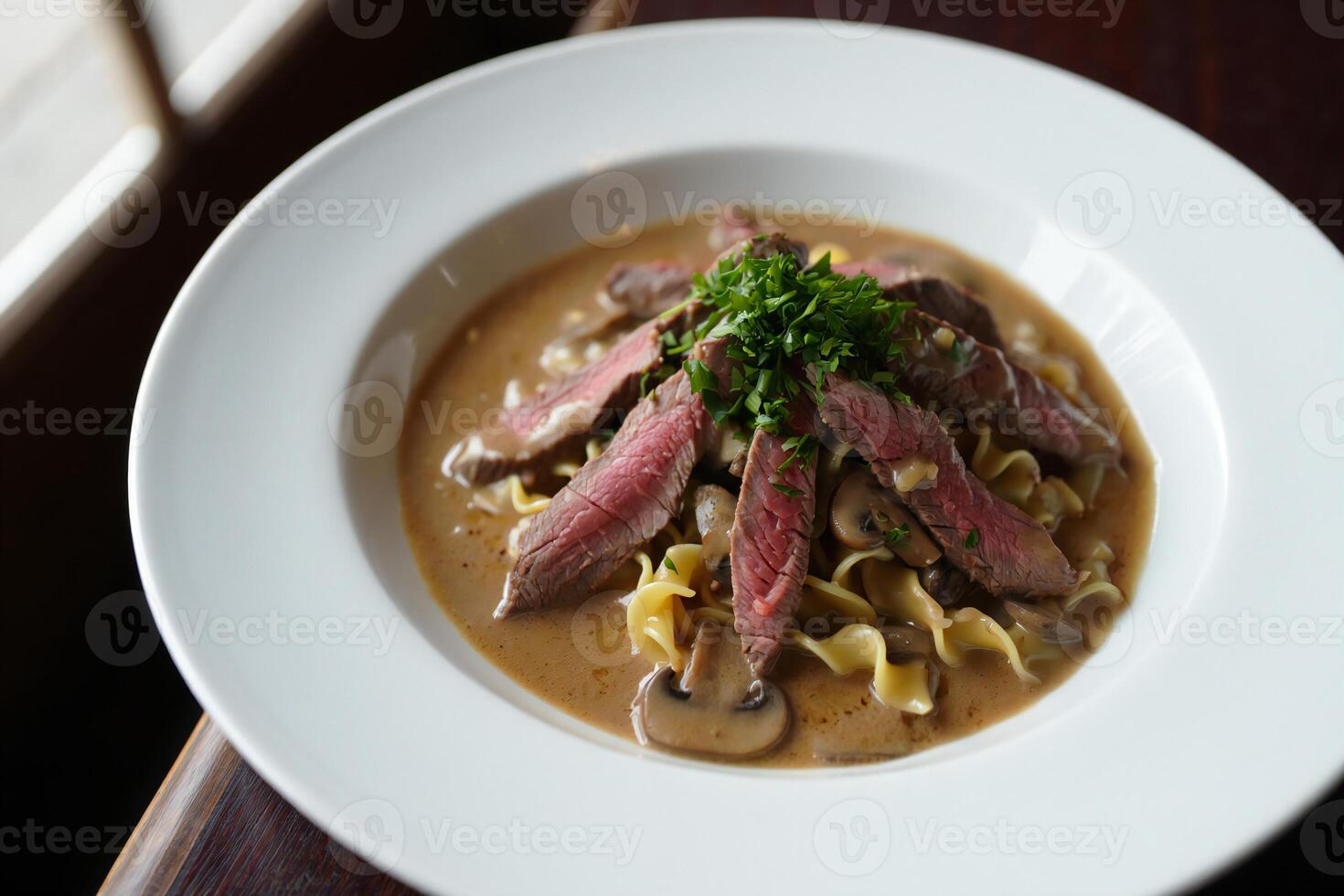 A plate of steak and noodles with a side of sauce photo