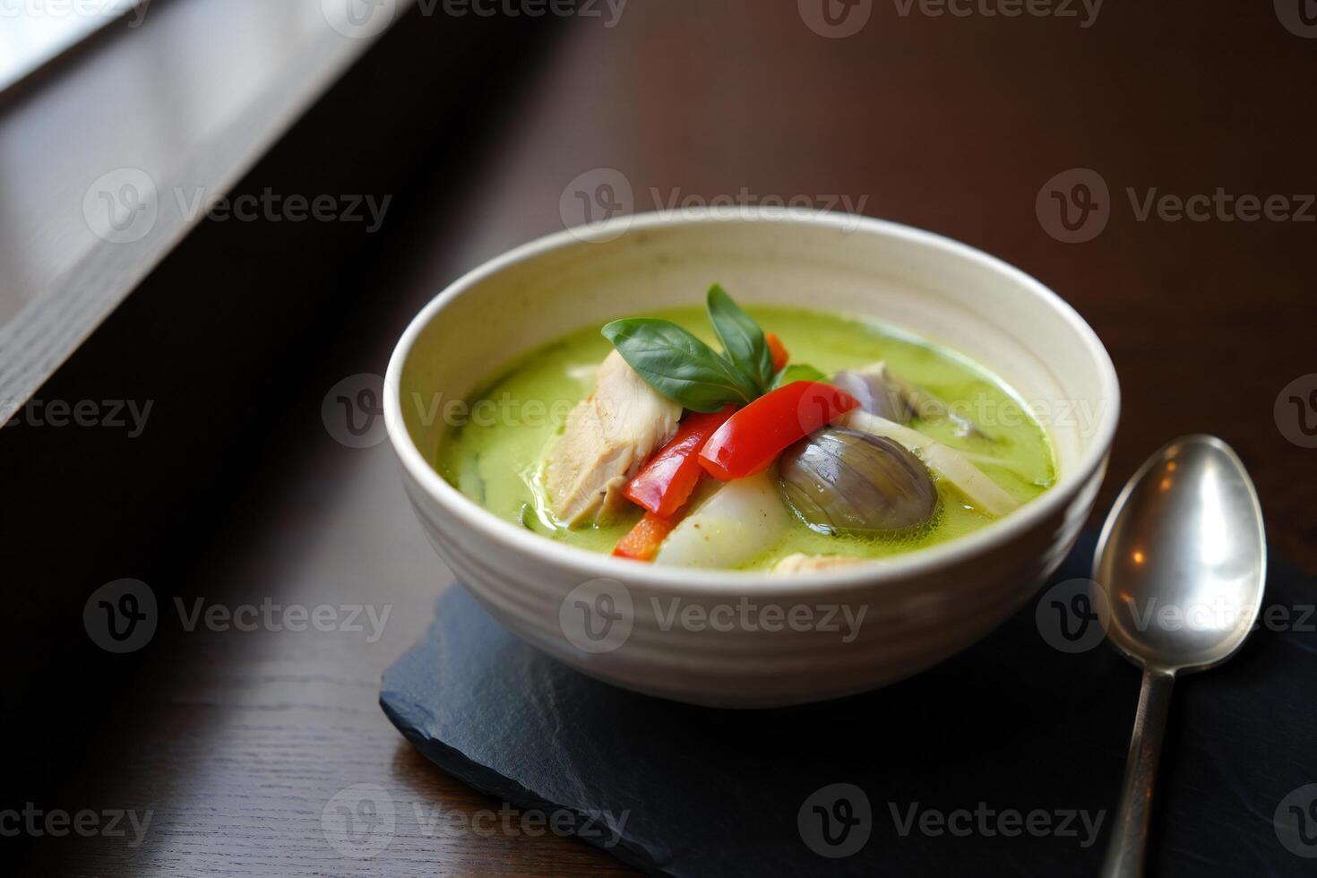 A bowl of soup with a spoon sitting on a table photo