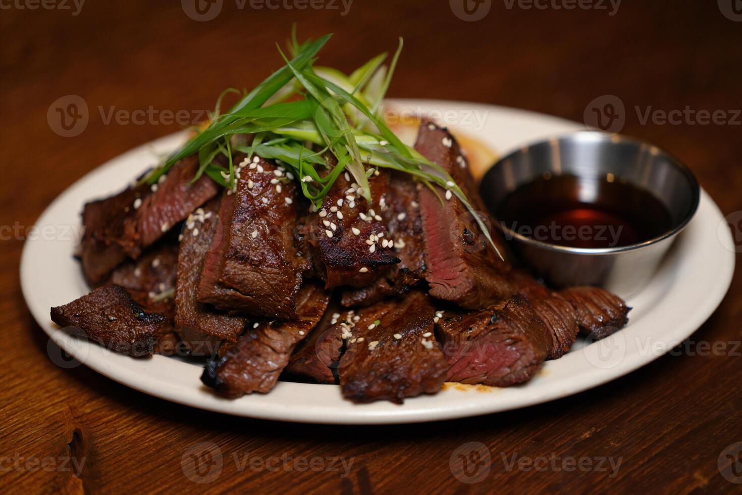 A plate of steak with a dipping sauce on it photo