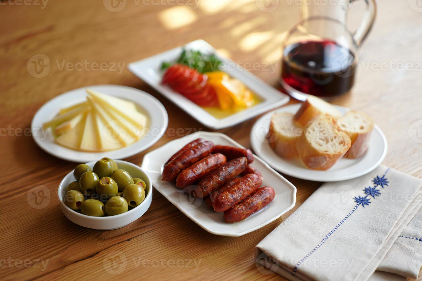 A table with a plate of food, a glass of wine and a bowl of olives photo