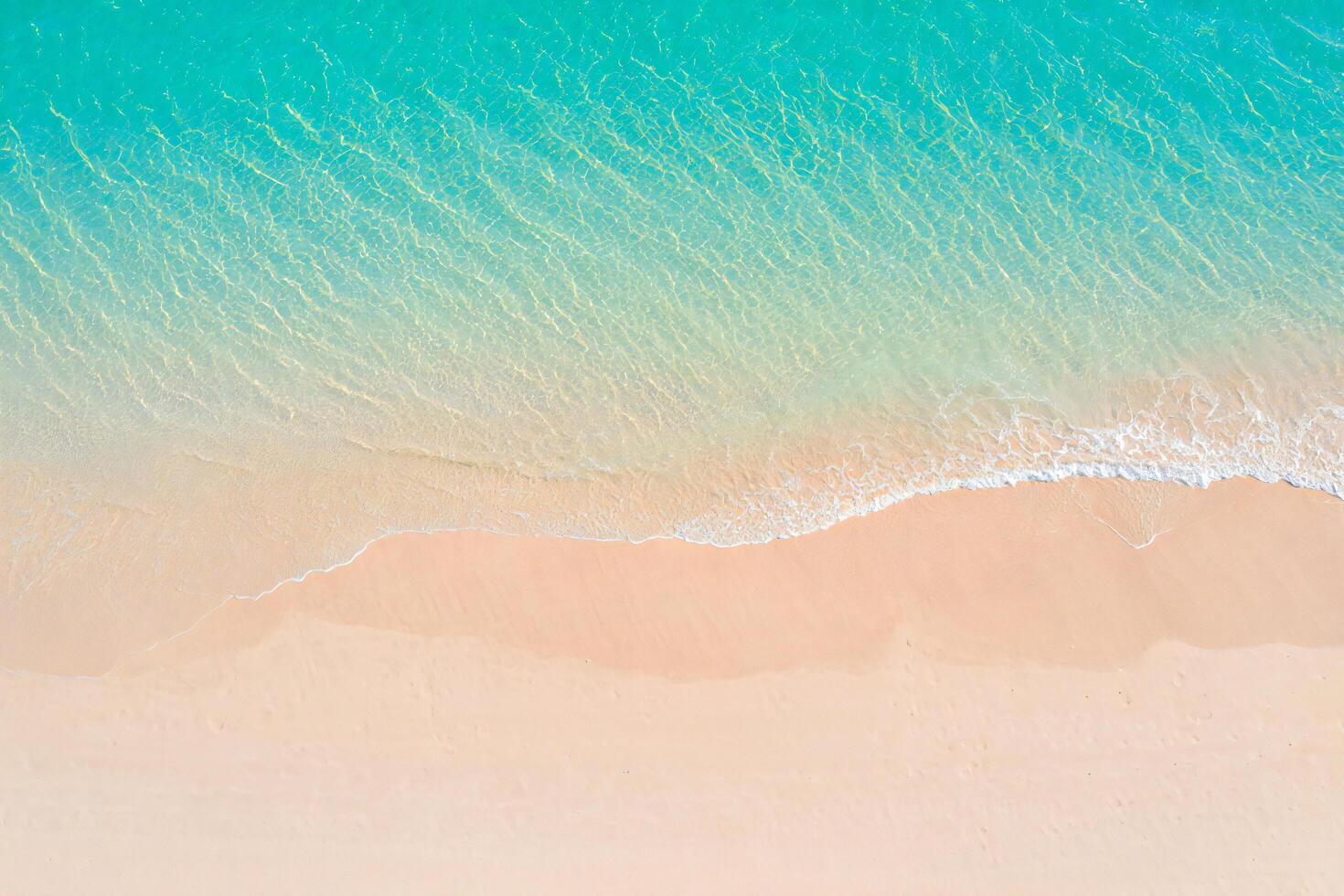 Beach Background Aerial View of Turquoise Ocean Waves Gently Crashing on a Pink Sandy Beach photo