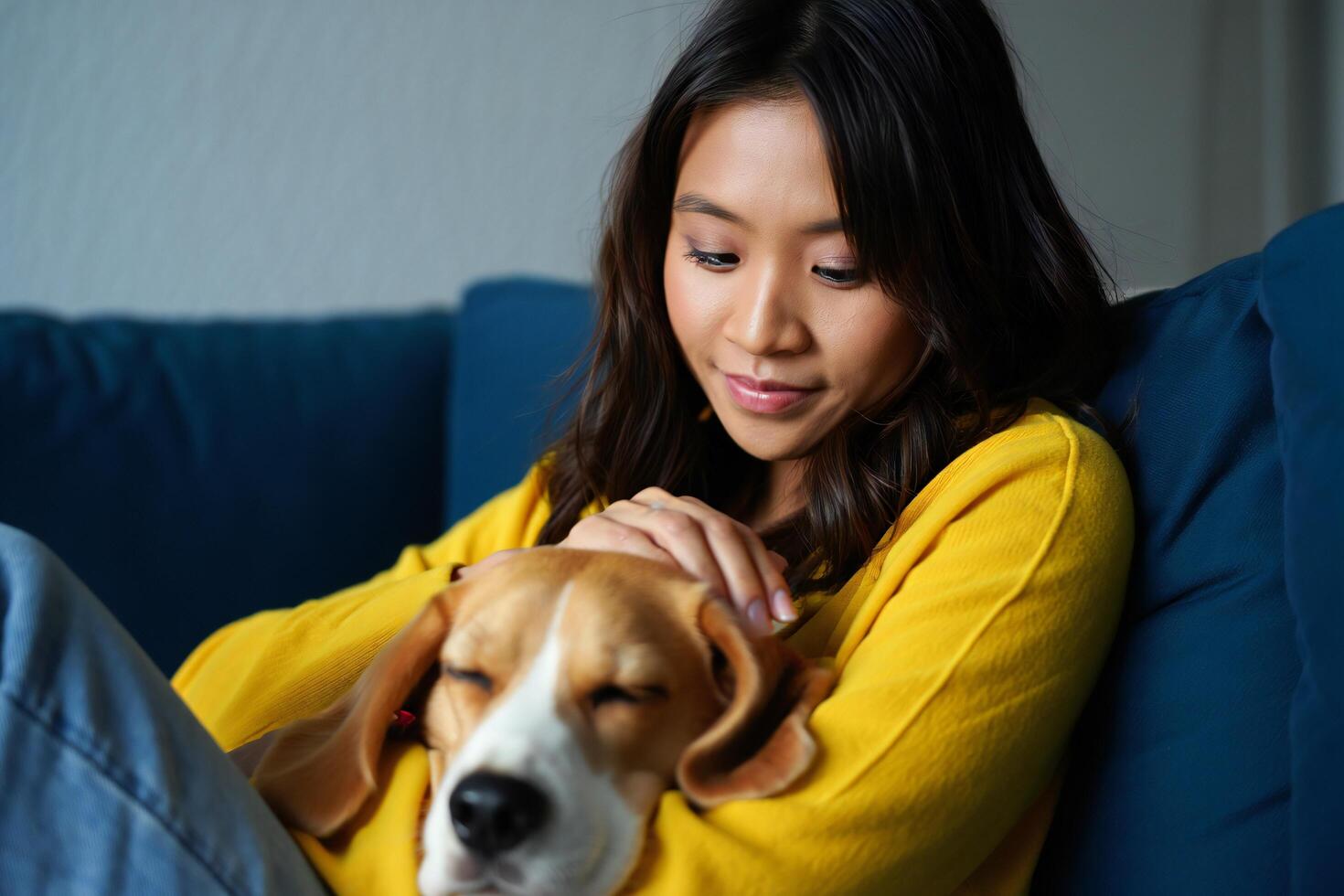 Dog Background Young Asian Woman Cuddles Beagle Dog on Couch Relaxed Home Scene photo