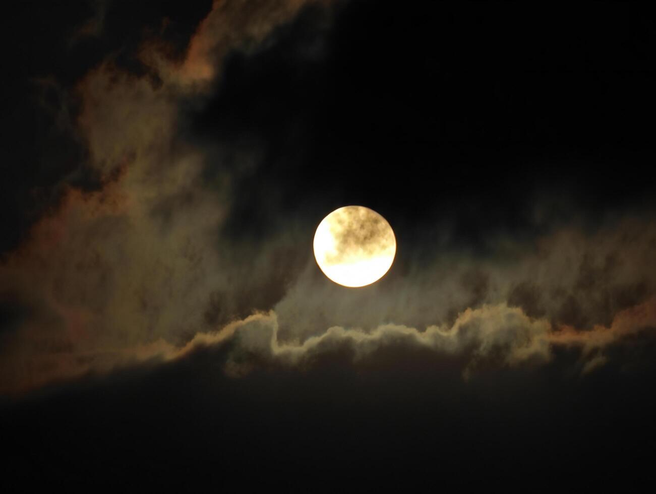 Halloween Background Enigmatic Full Moon Partially Hidden Behind Dark Clouds at Night photo