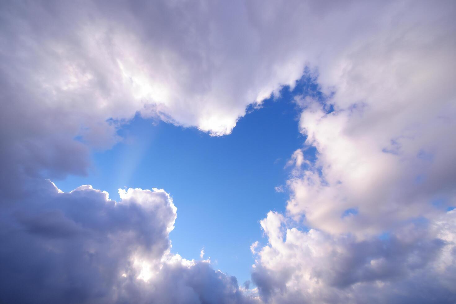 Nature Background Dramatic Blue Sky View with Puffy White and Grey Clouds Sunbeams Breaking Through photo