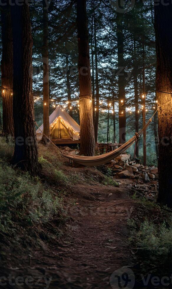 Peaceful forest camping scene with a hammock and illuminated tent under a canopy of trees photo