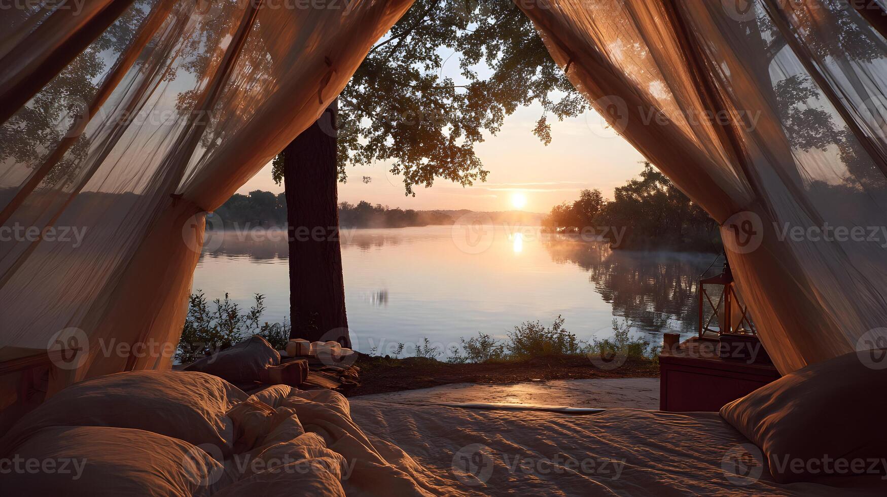 Lake view from a romantic camping tent during sunrise with cozy bed and draped sheer fabrics photo