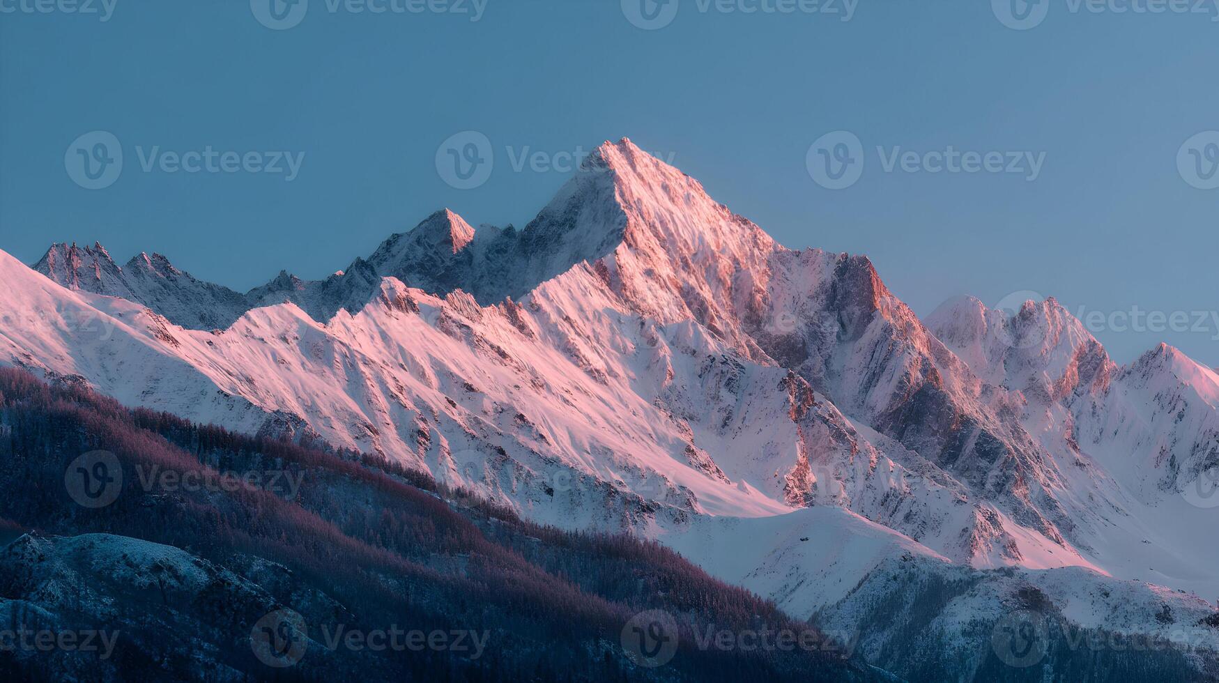 Majestic mountains covered in snow bathed in the warm glow of the setting sun against blue sky photo