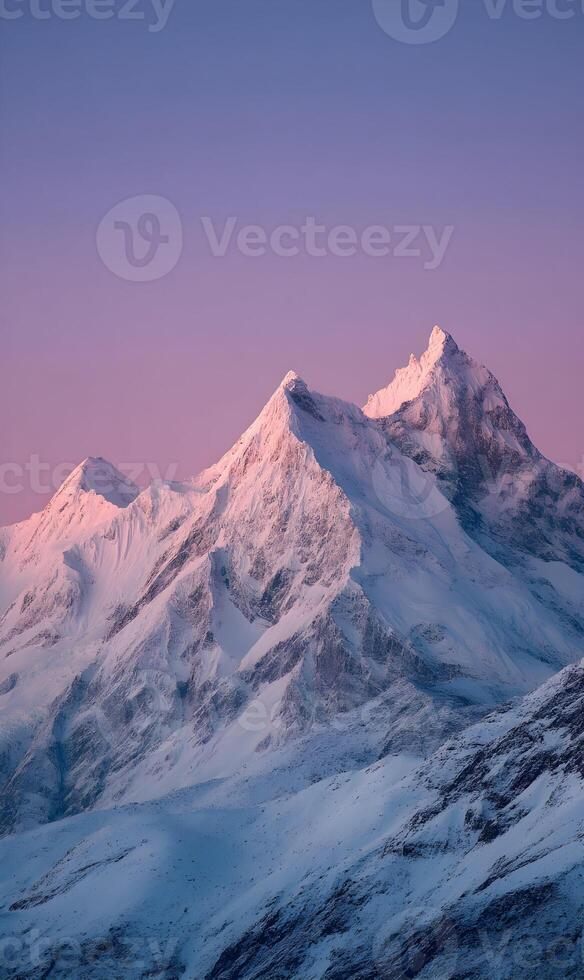 Majestic snow capped peaks glow under the warmth of early morning light and violet sky photo