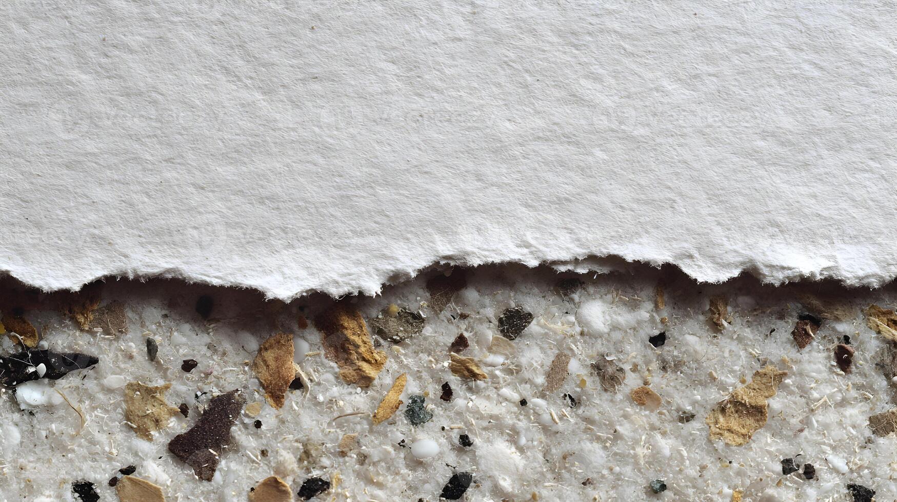 Abstract image showing a torn sheet of white paper against a textured surface with embedded material photo
