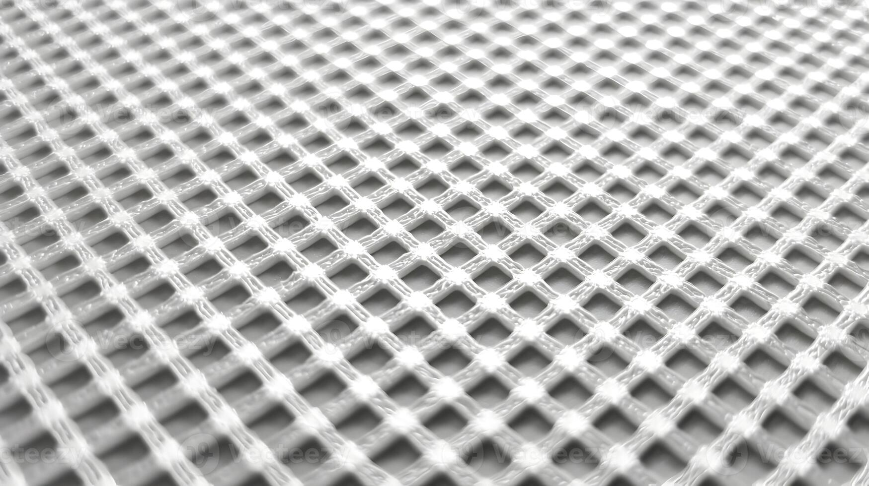 Close up perspective of a net like fabric with a white pattern against a neutral gray background photo