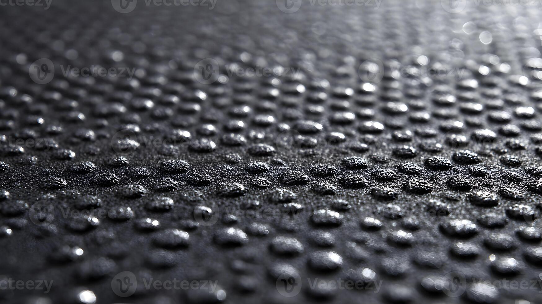 Close up photograph featuring water droplets on a dark textured surface creating an abstract look photo