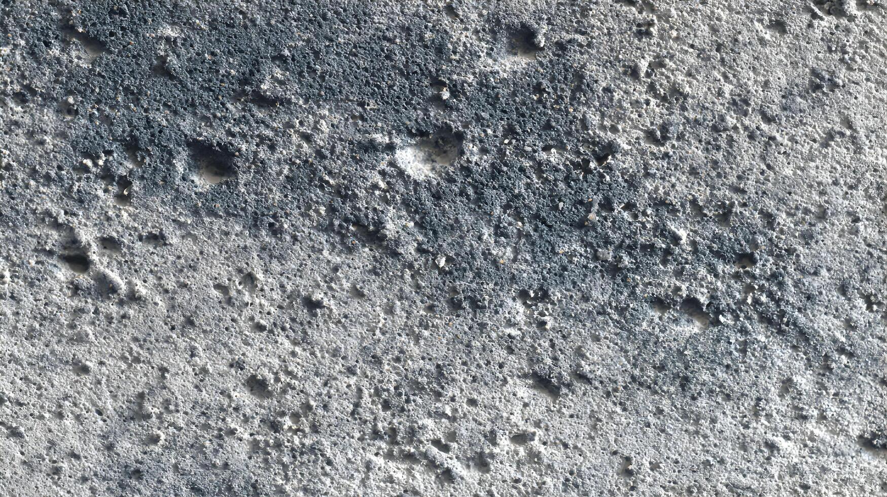 Textured surface of gray porous material with dark spots creating a rugged and weathered aesthetic photo