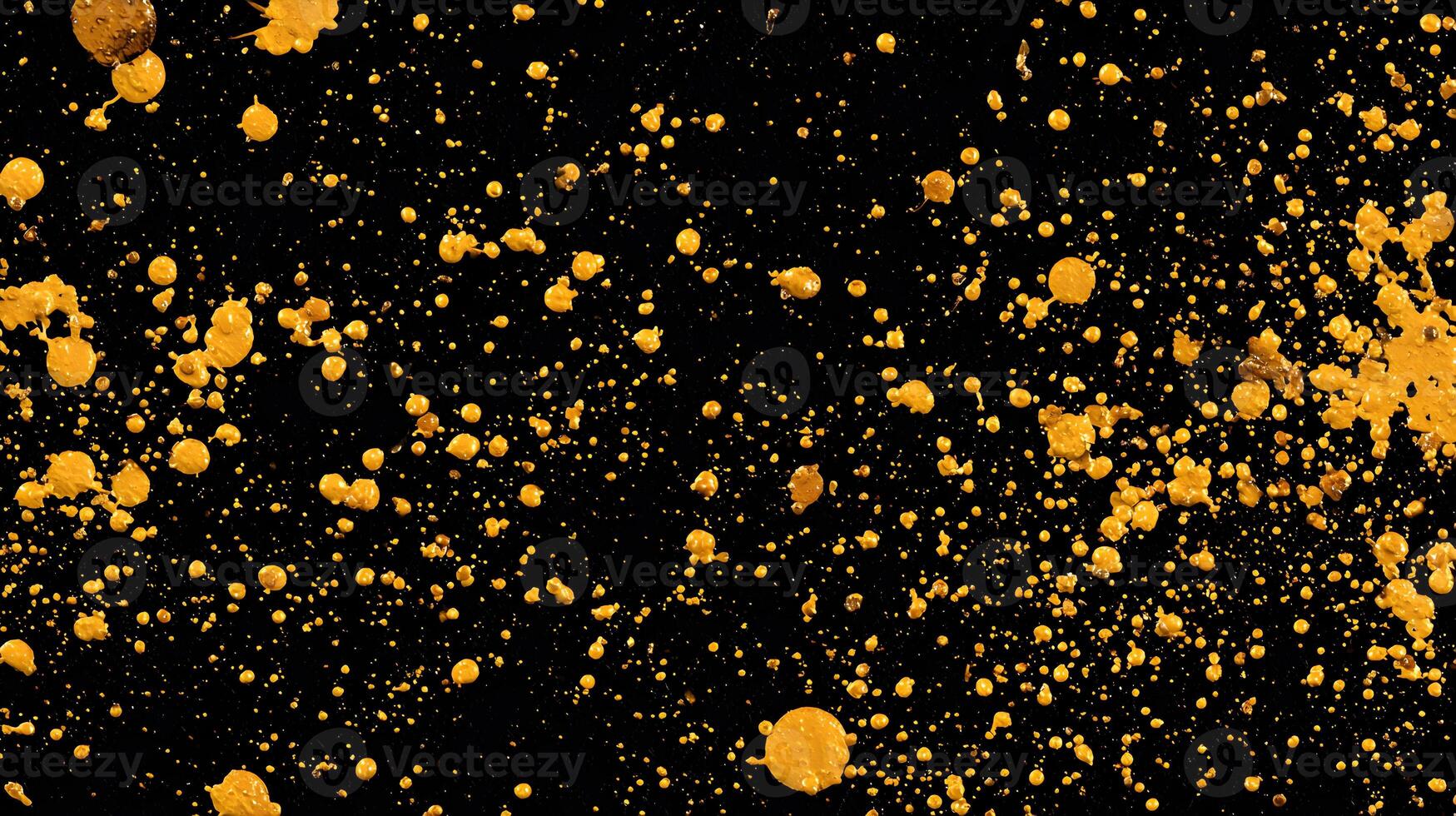 Dramatic gold paint splatters against a dark black background creating a striking abstract design photo