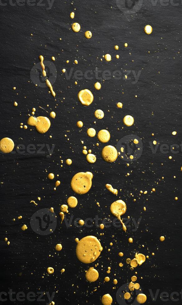 Gold splashes of abstract paint on black surface creating dynamic and artistic patterns of color and texture photo