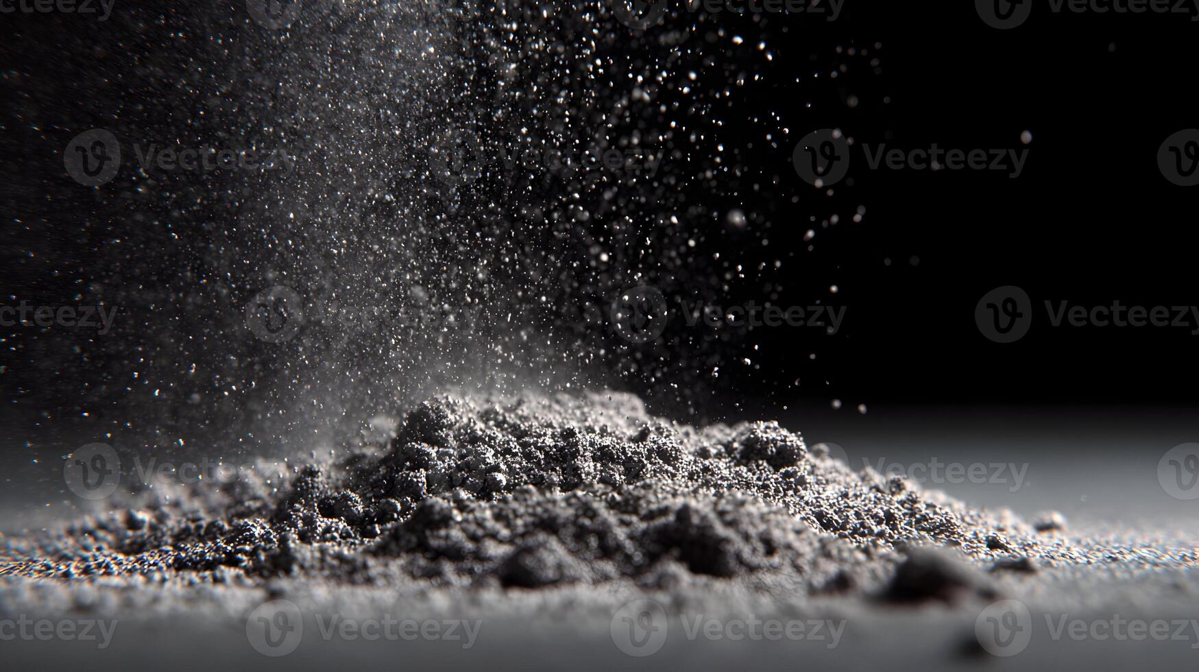 Dramatic monochrome shot of falling gray powder creating abstract textures with a dark background photo