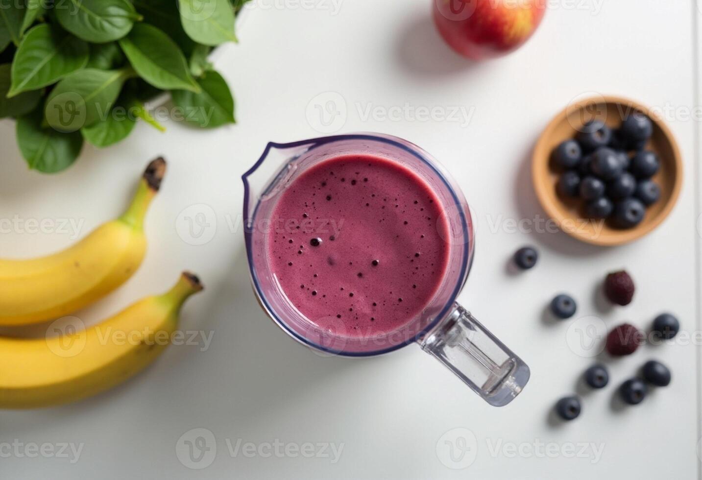 A blender with a blueberry smoothie next to bananas and blueberries photo
