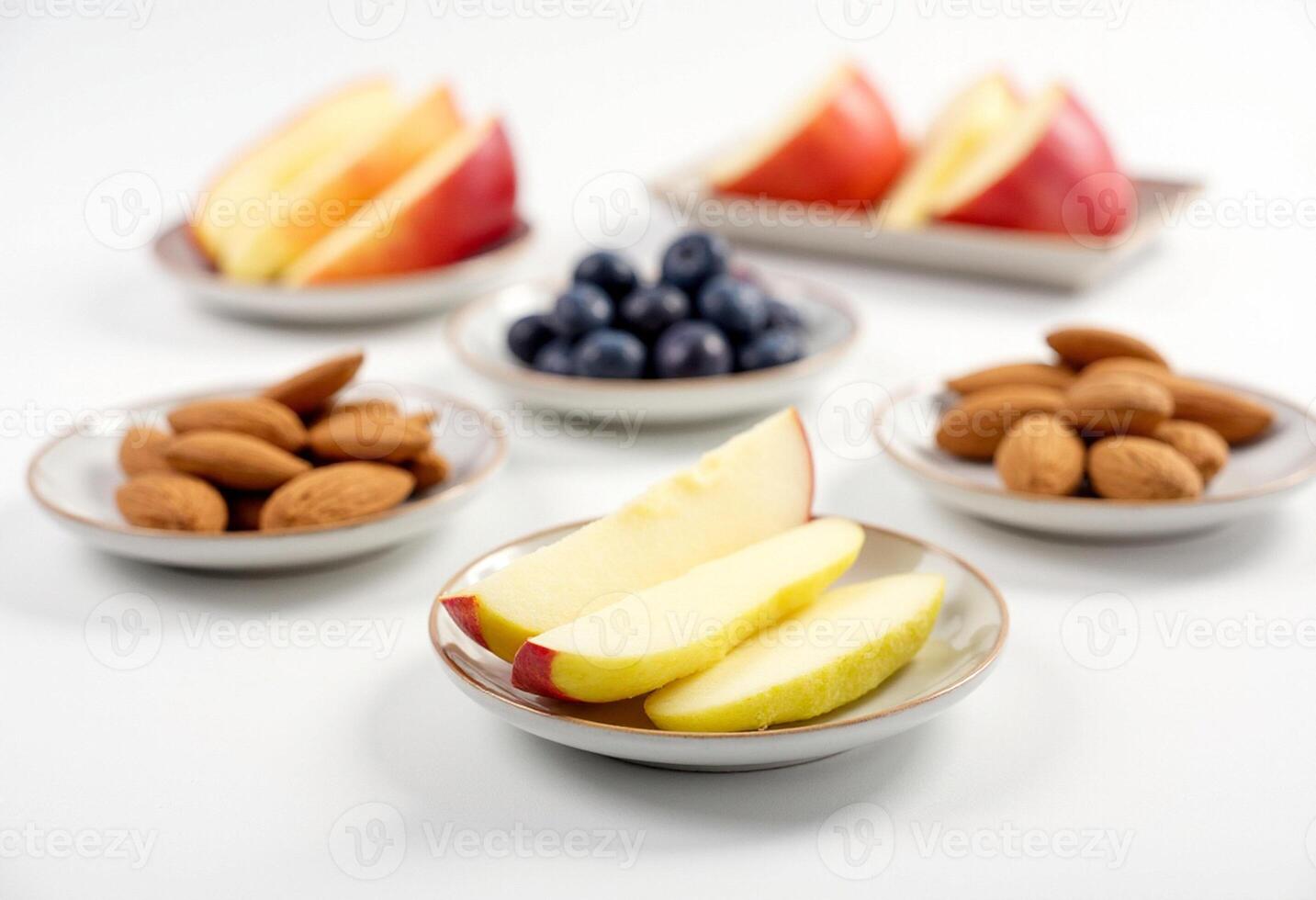 A bowl of sliced apples, almonds, blueberries and a banana photo