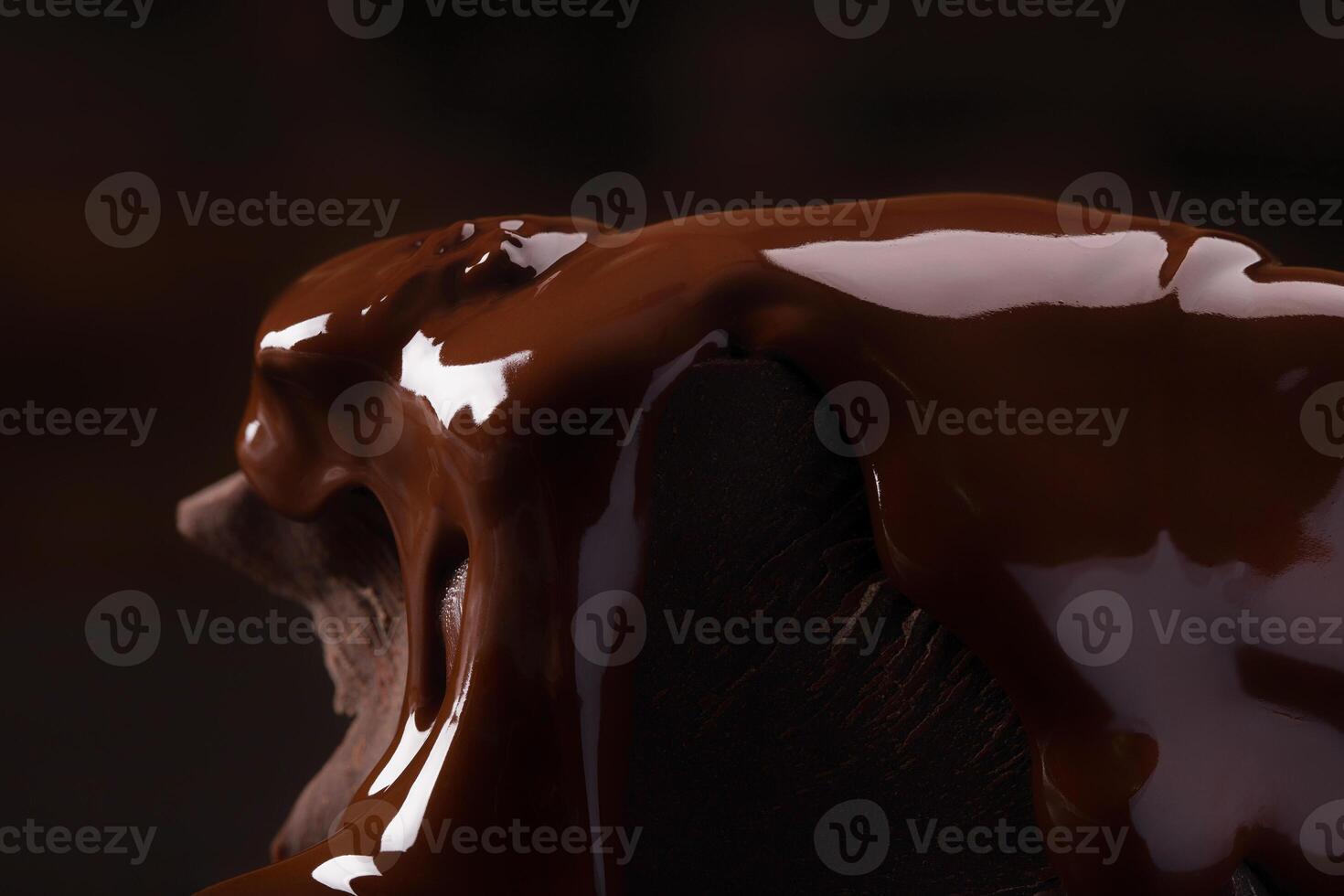 broken pieces pouring with melted chocolate on black table photo