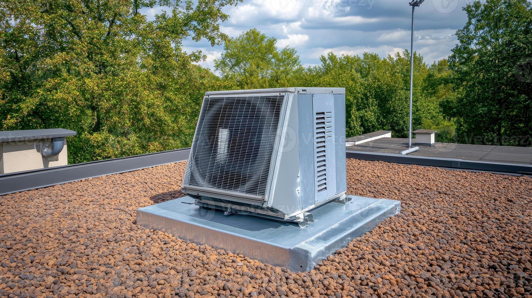 Rooftop HVAC Unit Central Air Conditioning on a Flat GravelCovered Roof with Green Tree Background photo