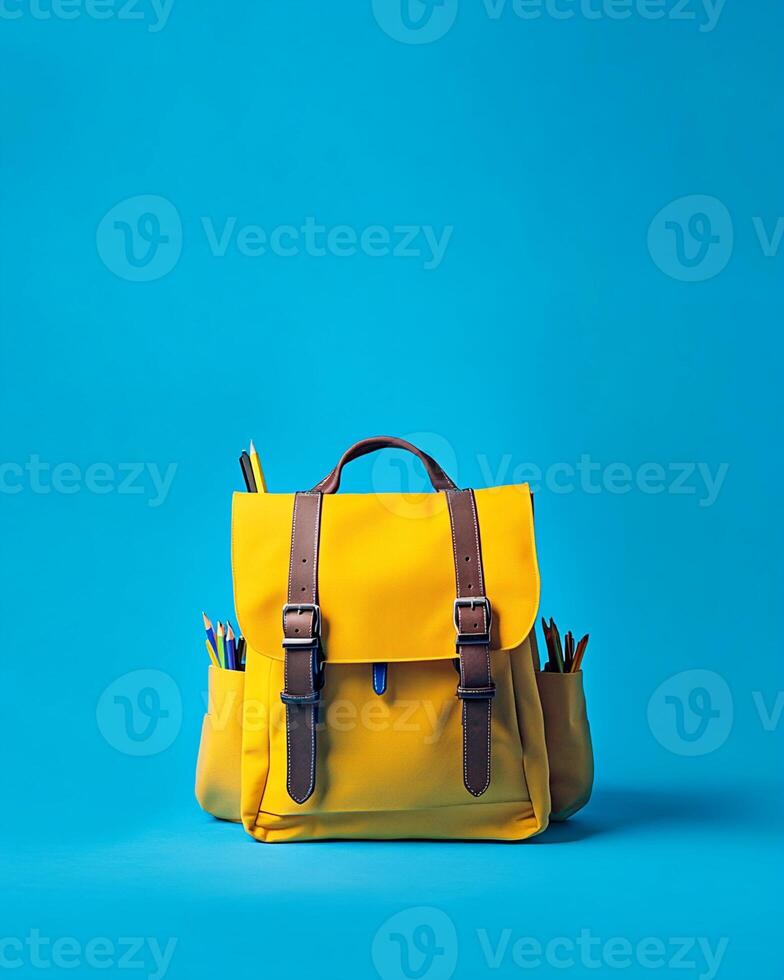 Yellow Backpack with Pencils on Blue Background photo
