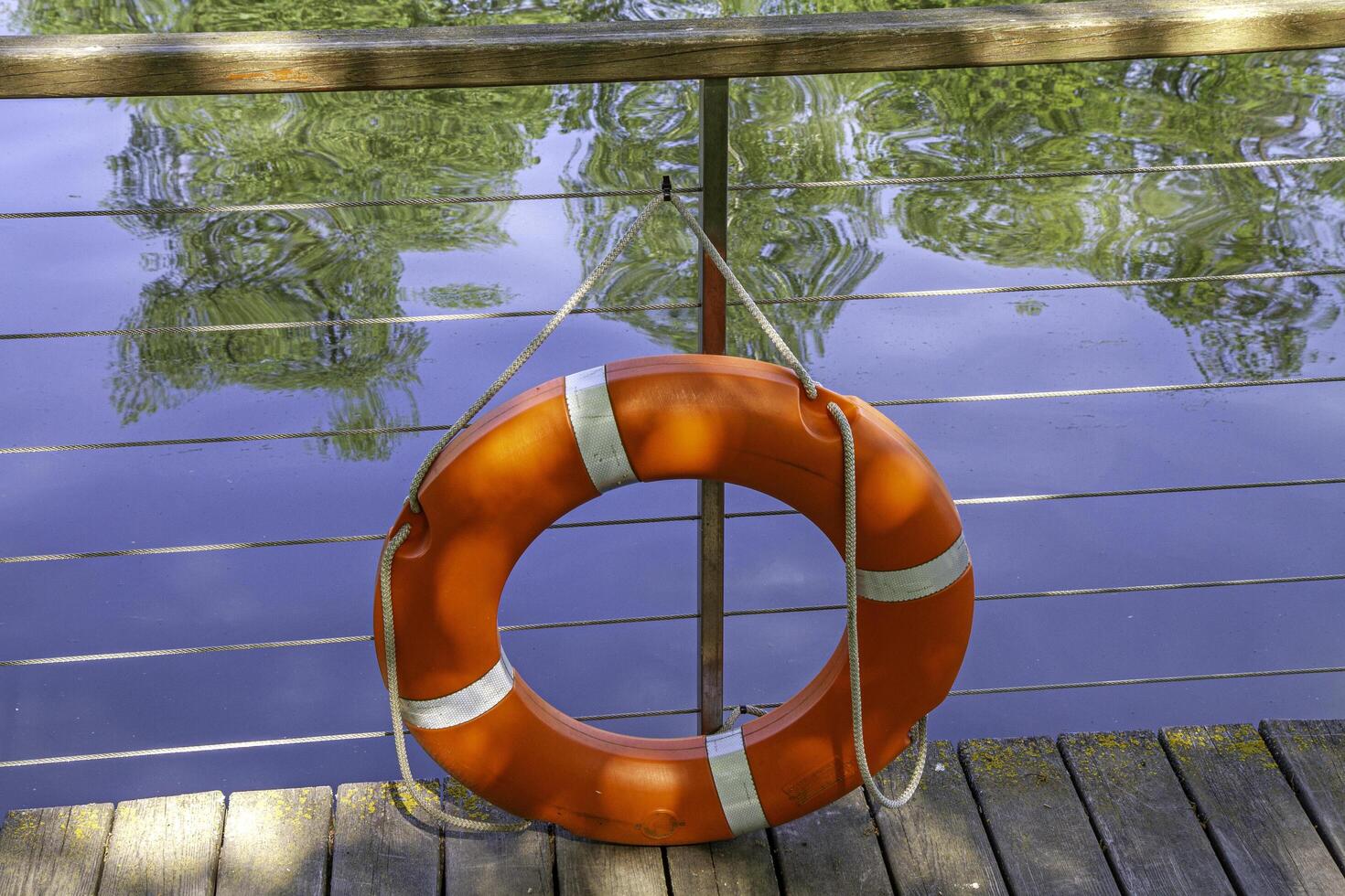 Lifebuoy on a wooden pier in calm water. photo