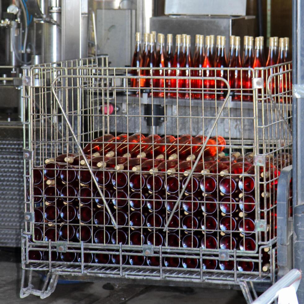 Industrial scene at a winery with a metal crate filled with bottles of rose wine. photo