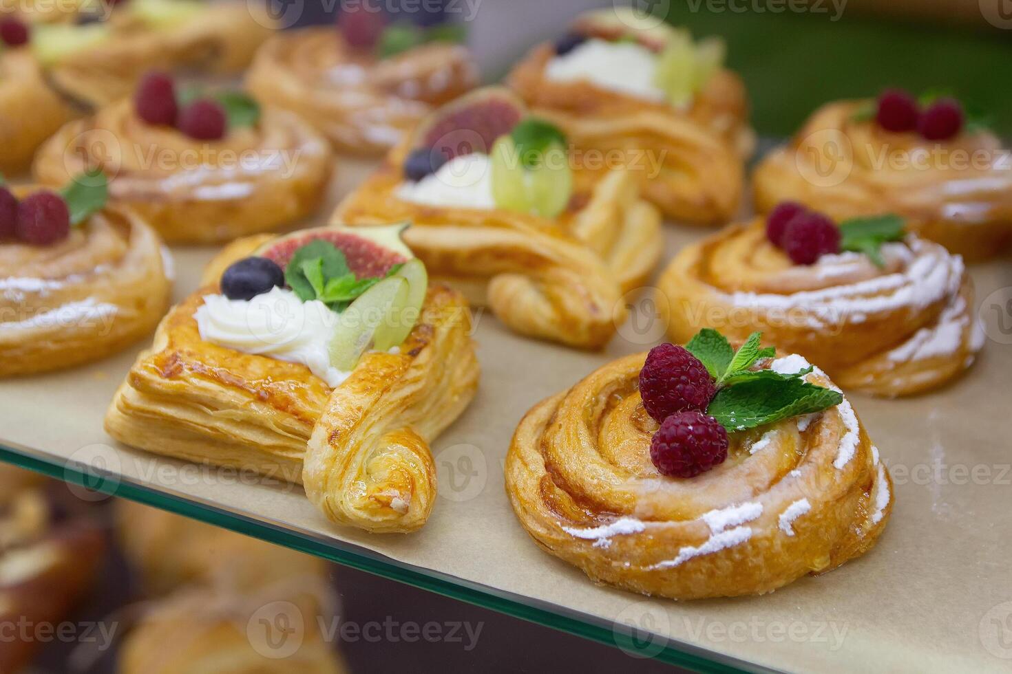 Delicious baking with berries and custard cream in glass showcase. Food photo