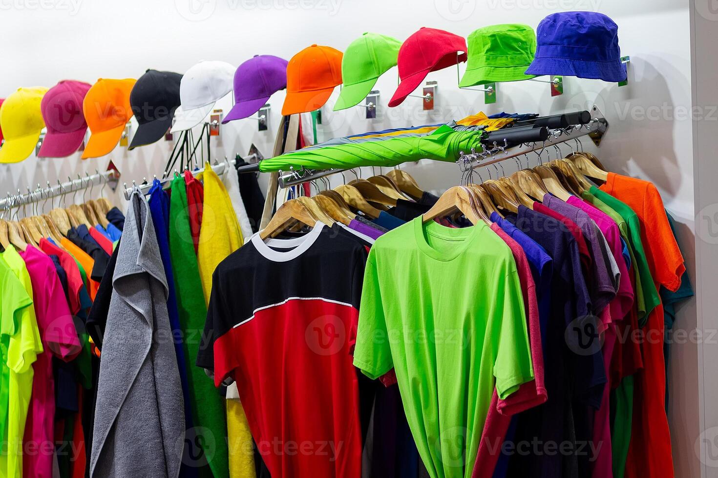 Multi-colored t-shirts and baseball caps on the window of a sports store photo