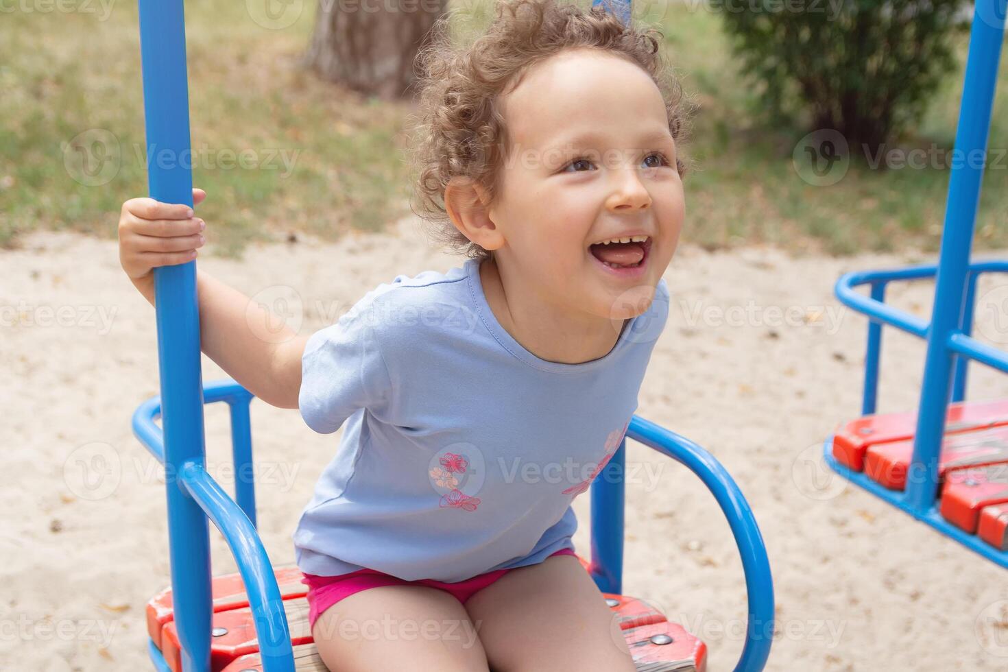 Curly child for swing in the summer park photo