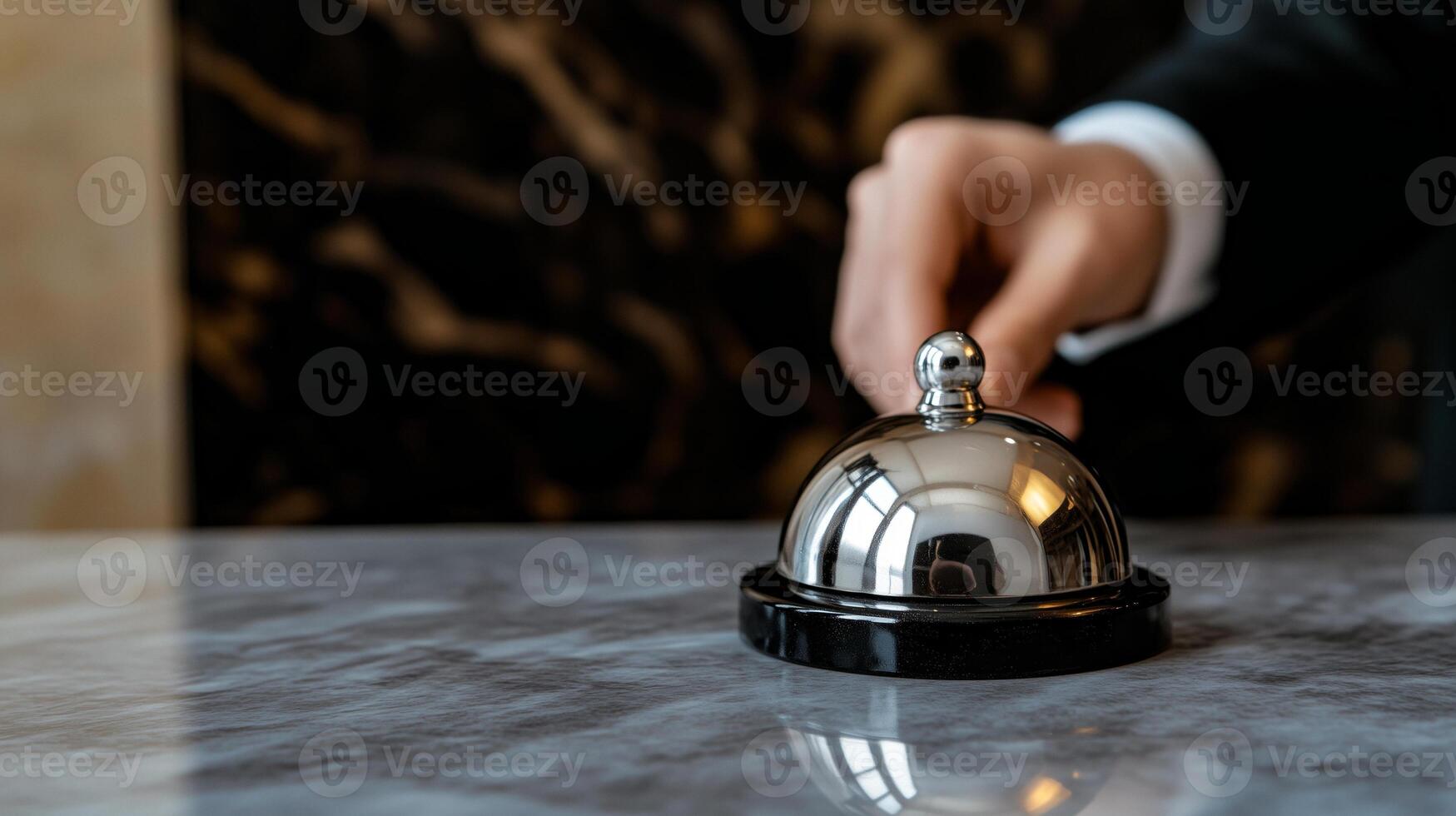 A person in a suit is holding a bell on a table photo