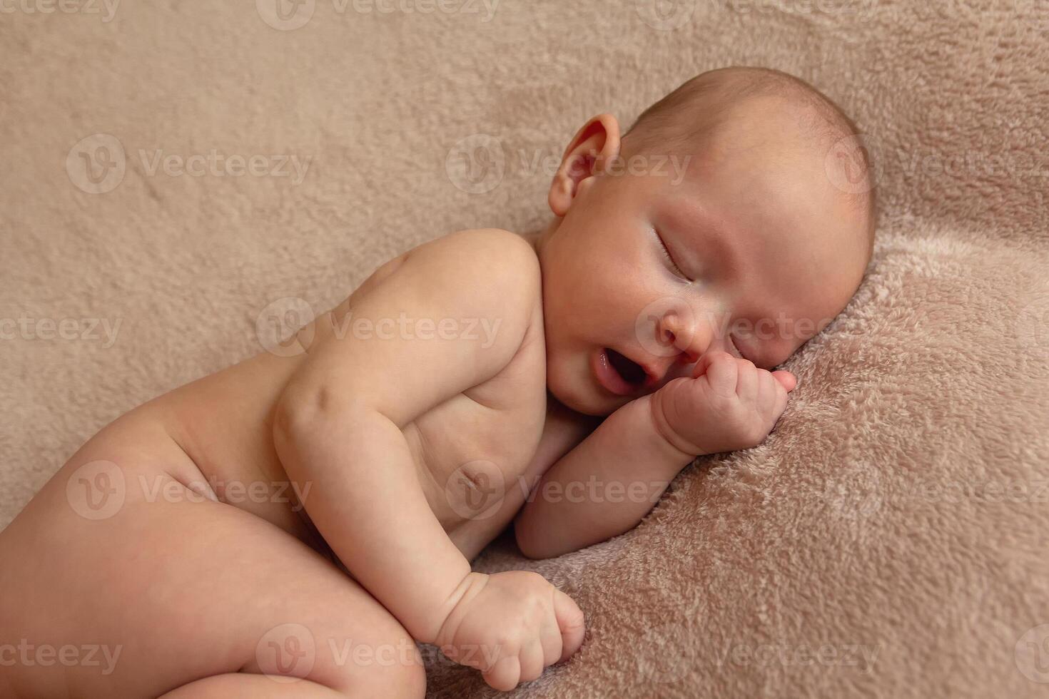 Cute little naked newborn child lies on a soft sheet photo