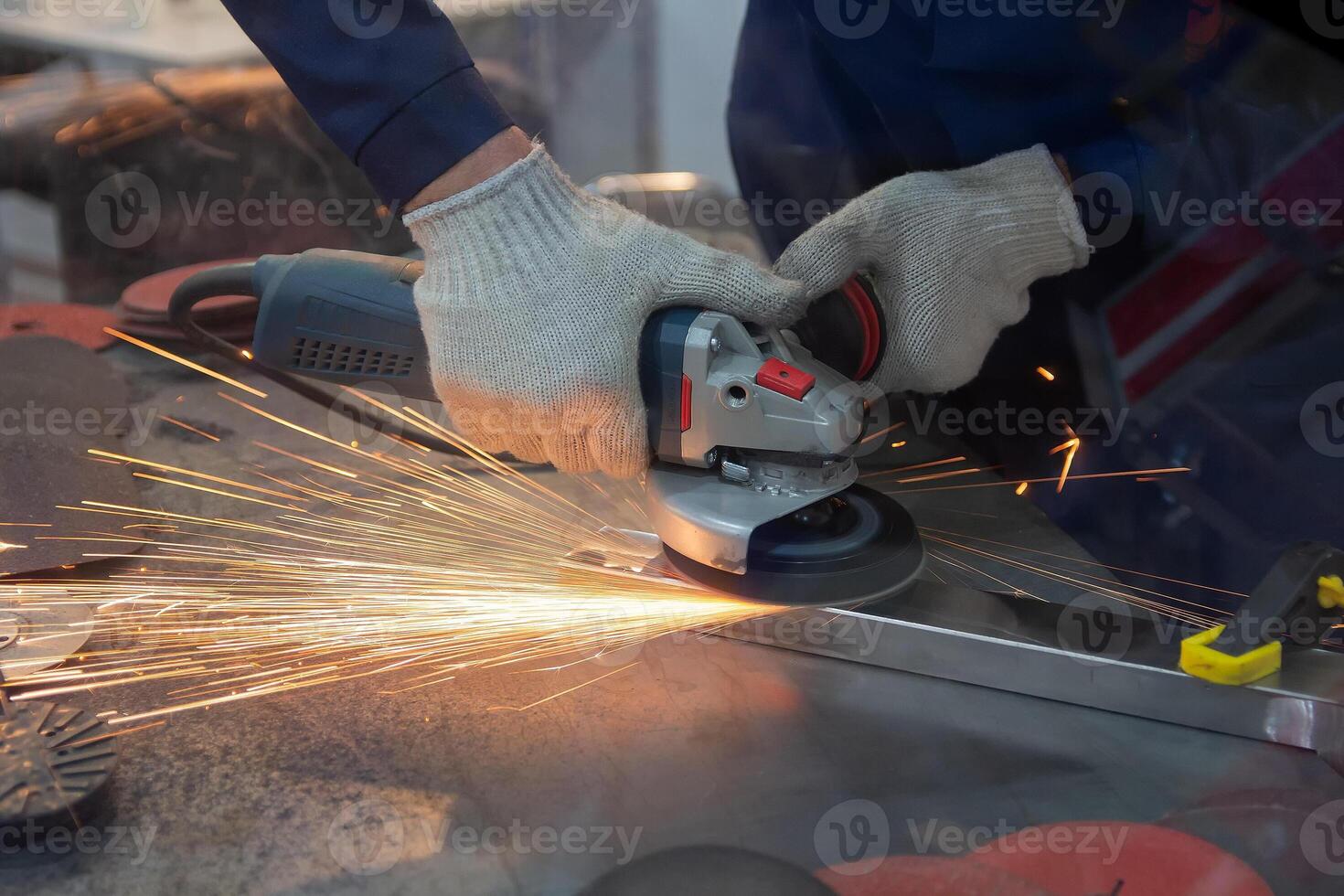 Mechanic using angle grinder and working with metal in workshop. Peoplr photo